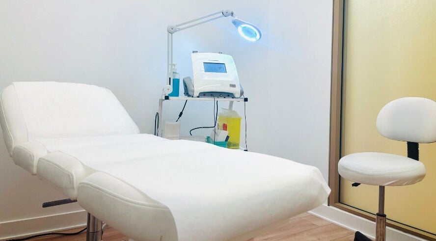 Cabine de soins moderne à Épilation L’élégance, Brossard, Québec, CA avec table de traitement blanche.