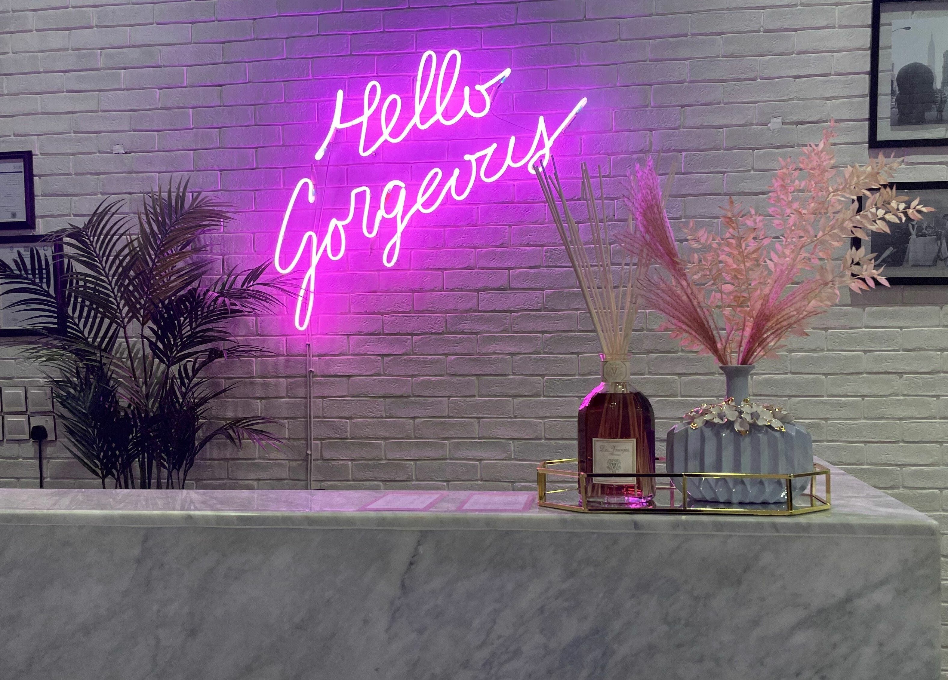 ديكور استقبال في Volume Blow-Dry Bar بالرياض، حيث الإضاءة النيونية والنباتات والزهور الجميلة تبرز الروعة.