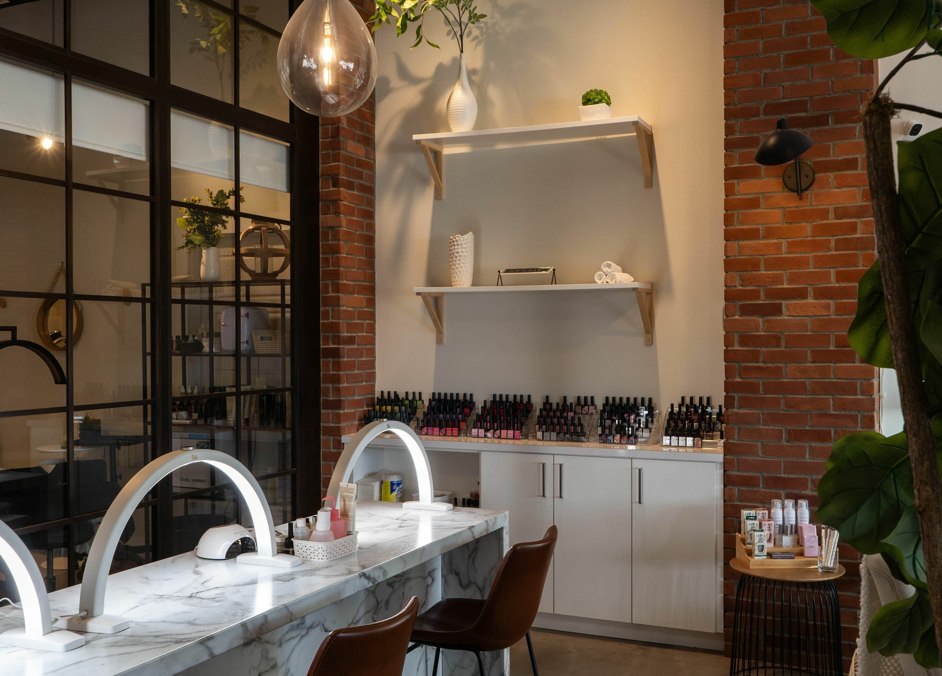 Modern nail salon station at SoFlo & Co North, Moncton, New Brunswick, CA with brick wall and sleek counters.