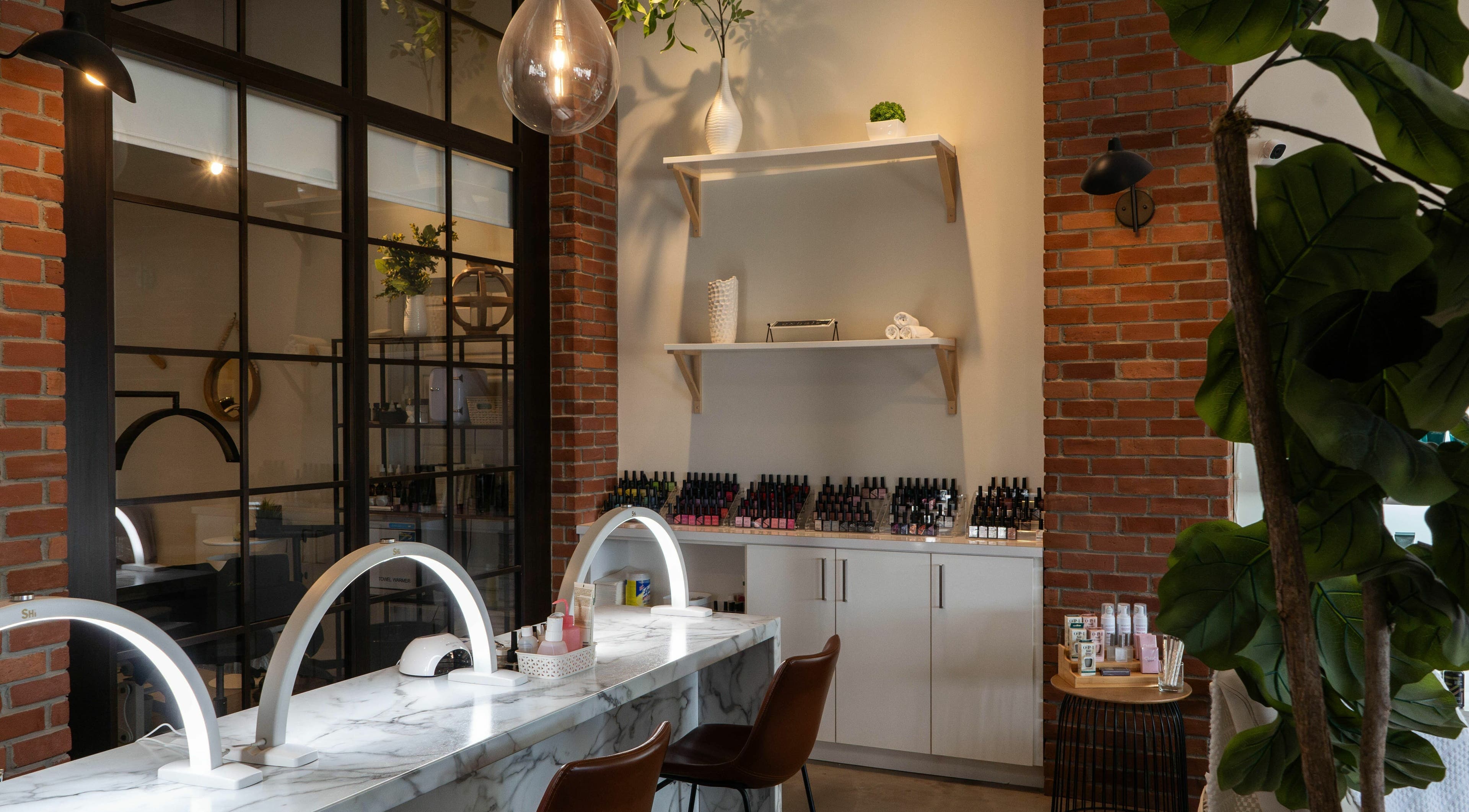 Modern nail salon station at SoFlo & Co North, Moncton, New Brunswick, CA with brick wall and sleek counters.