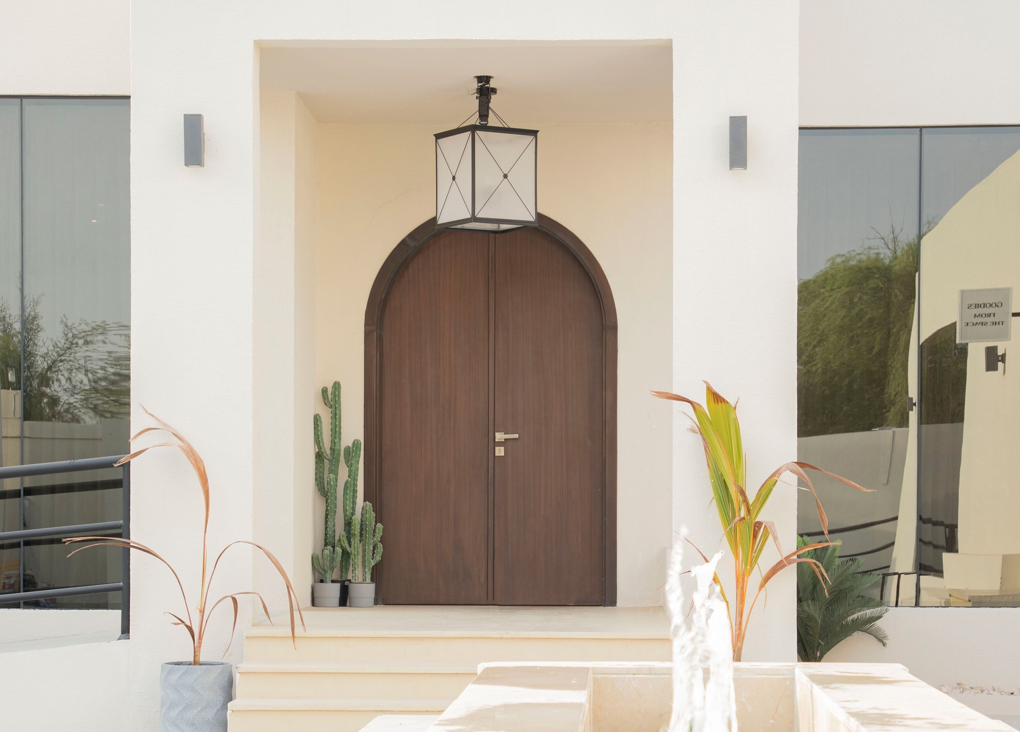 The Space Beauty Lounge entrance in Abu Dhabi, AE features a modern arch door with desert plants.