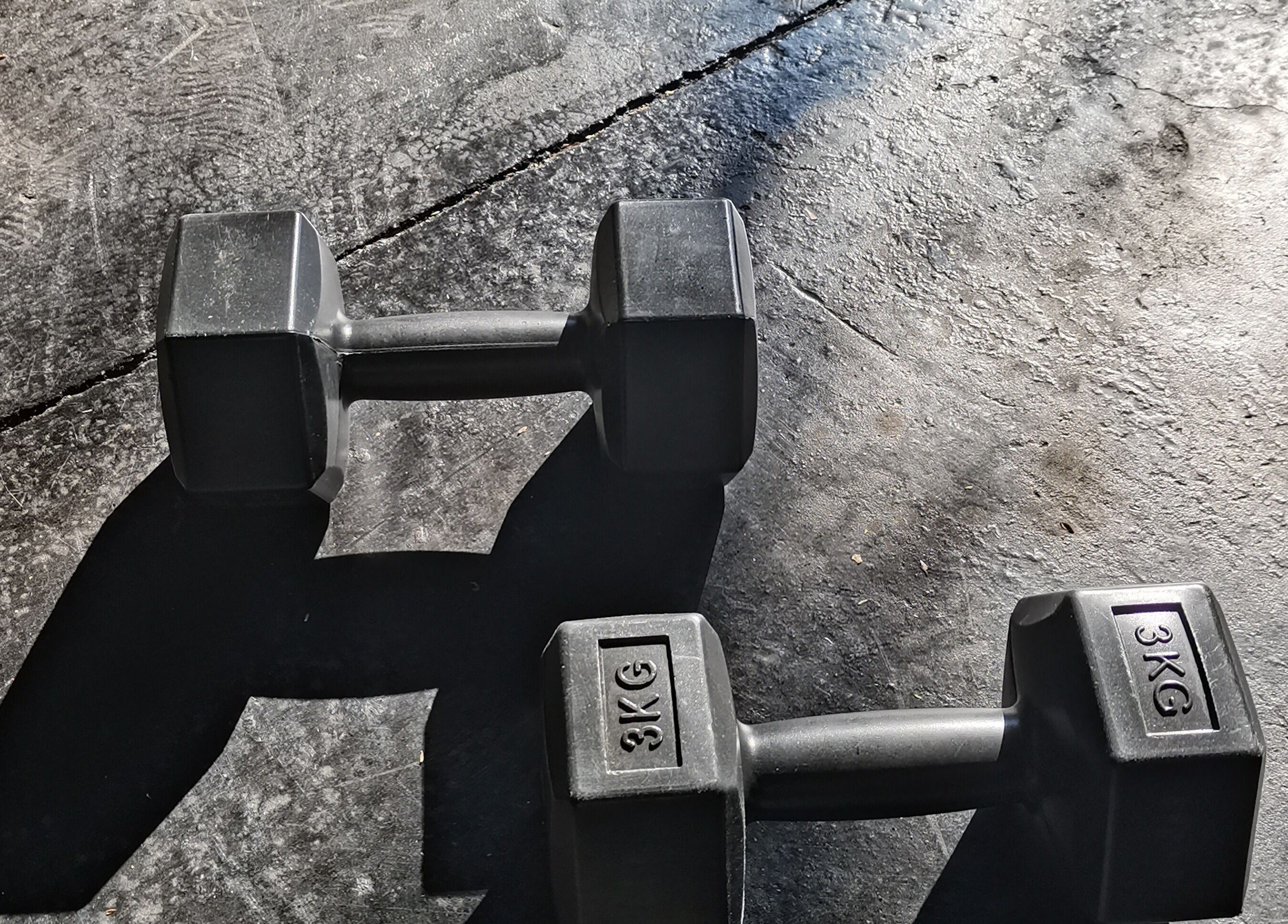 Black dumbbells casting shadows at Vita Amici, Vanderbijlpark, Gauteng, ZA. Perfect for fitness enthusiasts.