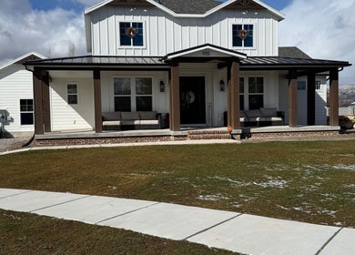 Front view of Nails By Janie in Lehi, Utah, US. Cozy seating on a wooden porch under a clear sky.