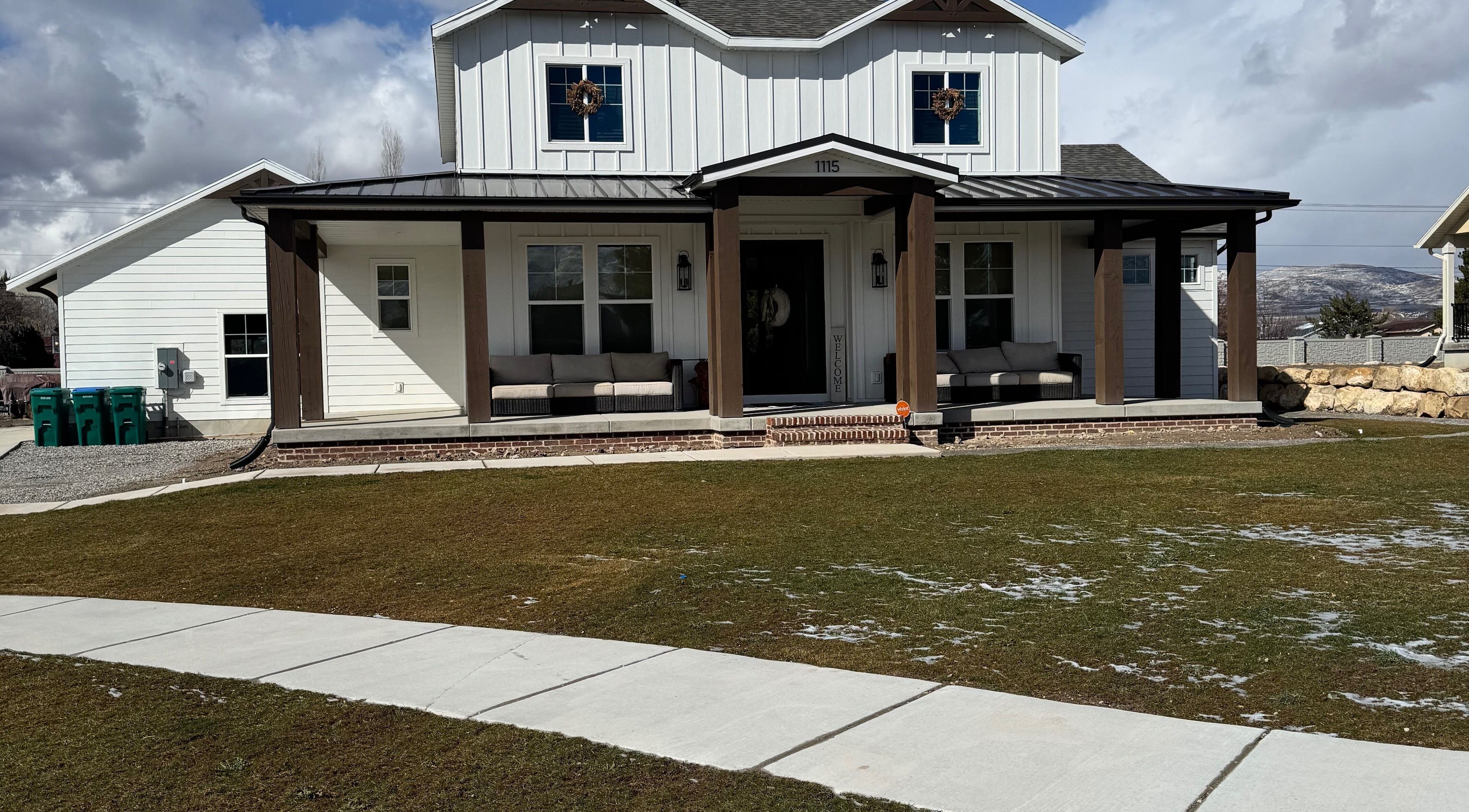 Front view of Nails By Janie in Lehi, Utah, US. Cozy seating on a wooden porch under a clear sky.