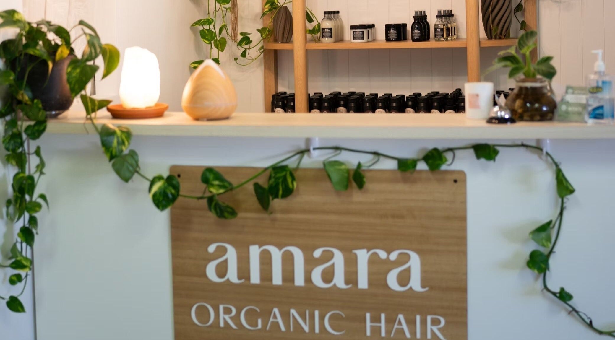 Reception at Amara Organic Hair, Burleigh Heads with lush plants and organic products displayed.