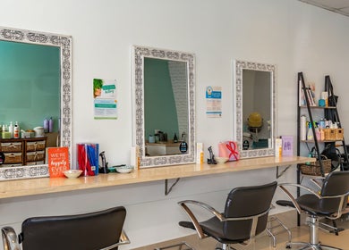 Elegant salon setup at Hideaway Hair in Moffat Beach, Queensland, AU, featuring stylish mirrors and seating.