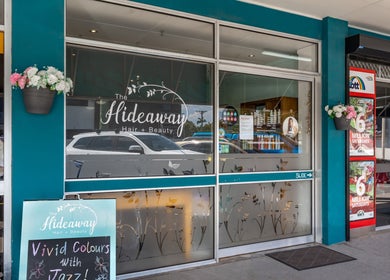 Exterior view of Hideaway Hair on Moffat Beach, Queensland, AU showcasing entrance and vibrant signage.