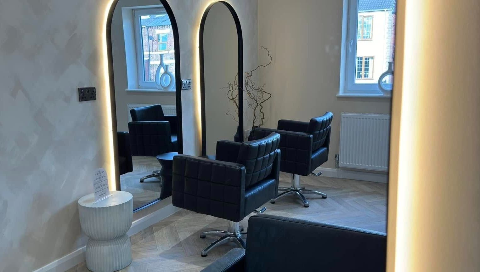 Sophisticated interior view of The Booth salon, Shafton, England, GB, featuring sleek chairs and illuminated mirrors.