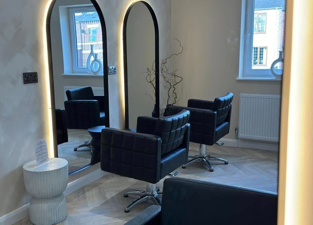 Sophisticated interior view of The Booth salon, Shafton, England, GB, featuring sleek chairs and illuminated mirrors.