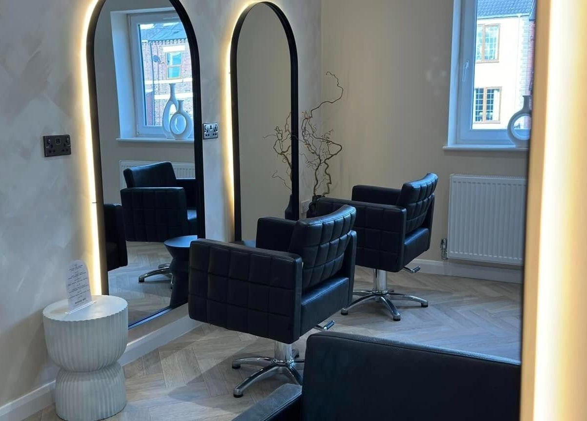 Sophisticated interior view of The Booth salon, Shafton, England, GB, featuring sleek chairs and illuminated mirrors.