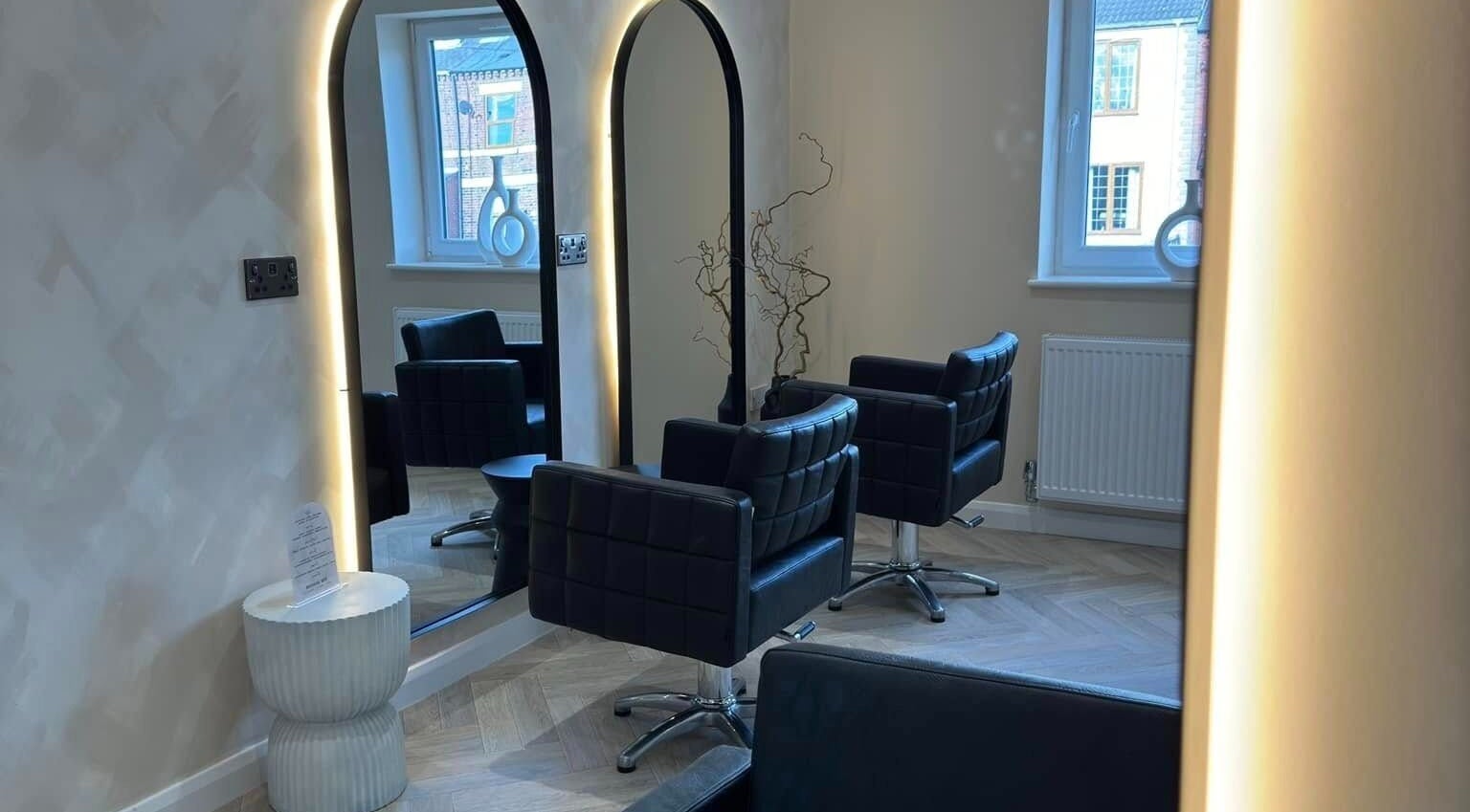 Sophisticated interior view of The Booth salon, Shafton, England, GB, featuring sleek chairs and illuminated mirrors.