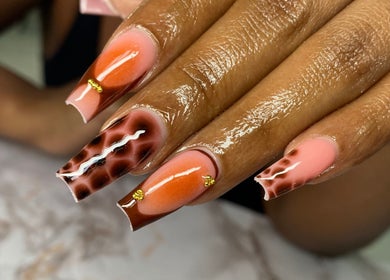 Detailed nail art at Atinas’ Nail Studio in Oistins, Christ Church, BB. Vibrant orange and brown designs.