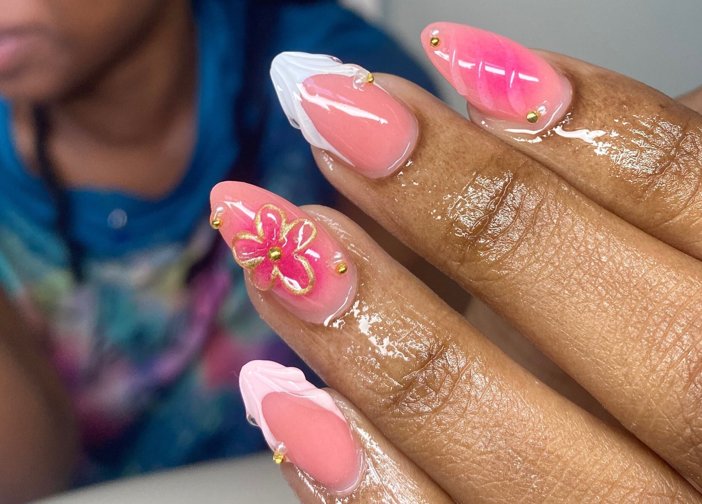 Floral nail art design at Atinas' Nail Studio, Oistins, Christ Church, BB. Vibrant pink and white hues with gold accents.
