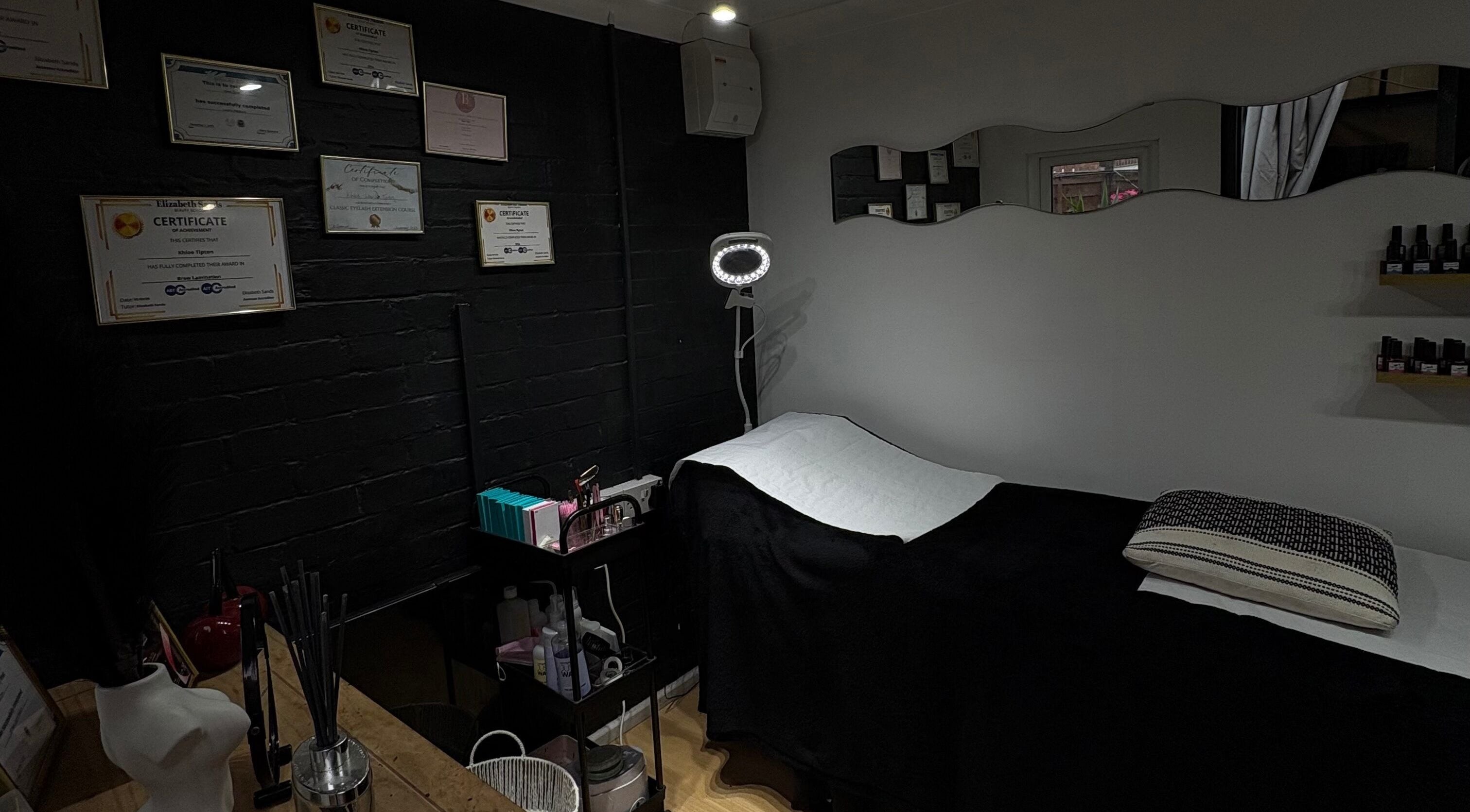 A serene treatment room at Builder and Brows by Khloe, Sandy, England, GB, showcasing certificates and a therapy bed.