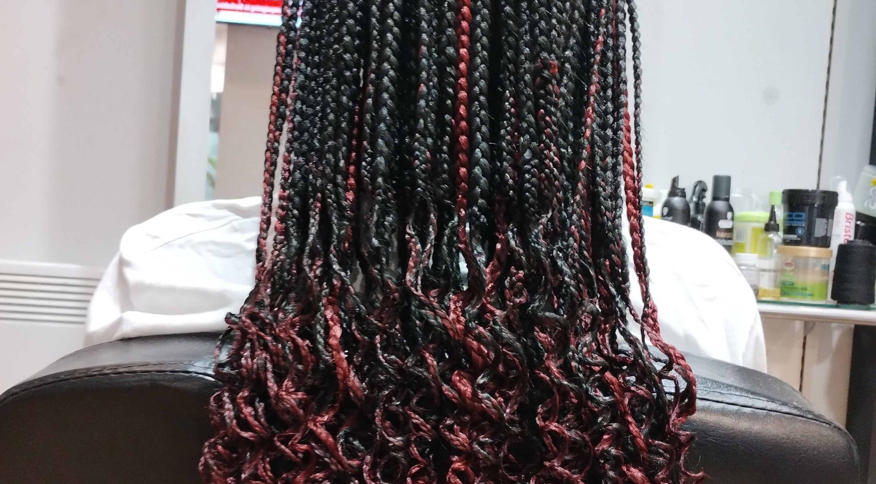 Intricate black and red braids styled at AmiCable Braids, Grantham, England, GB.
