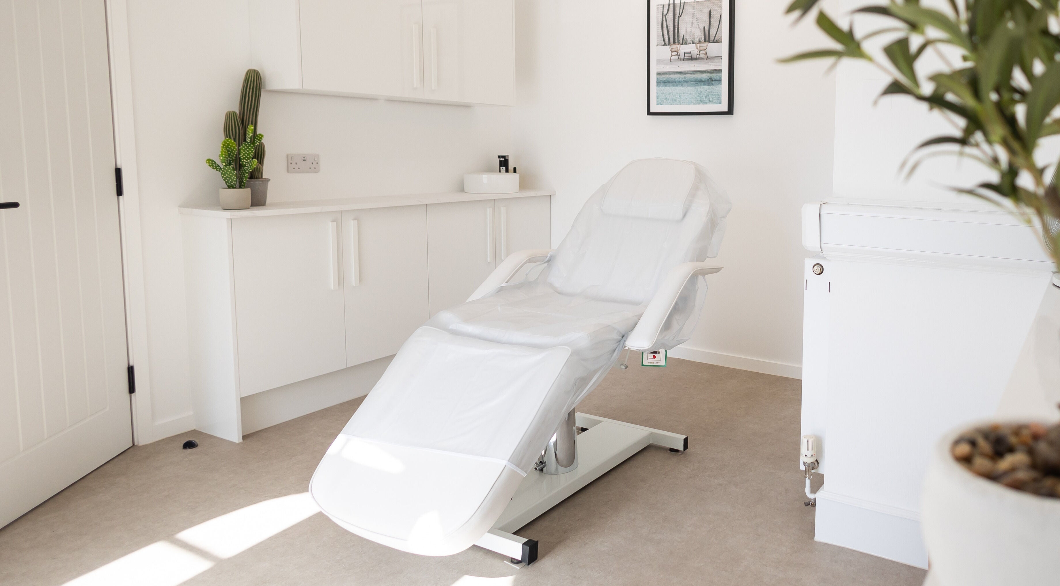 Calm, modern treatment room at Be. Laser and Skin Clinic, Taunton, England, GB, with a spa chair and plants.
