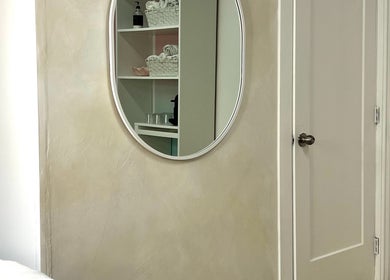 Elegant oval mirror in serene room corner at Palm, Montréal, Québec, CA.