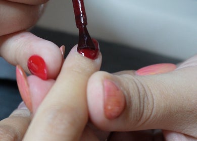 Nail polish application at Palm, Montréal, Québec, CA. Elegant red nails in progress.