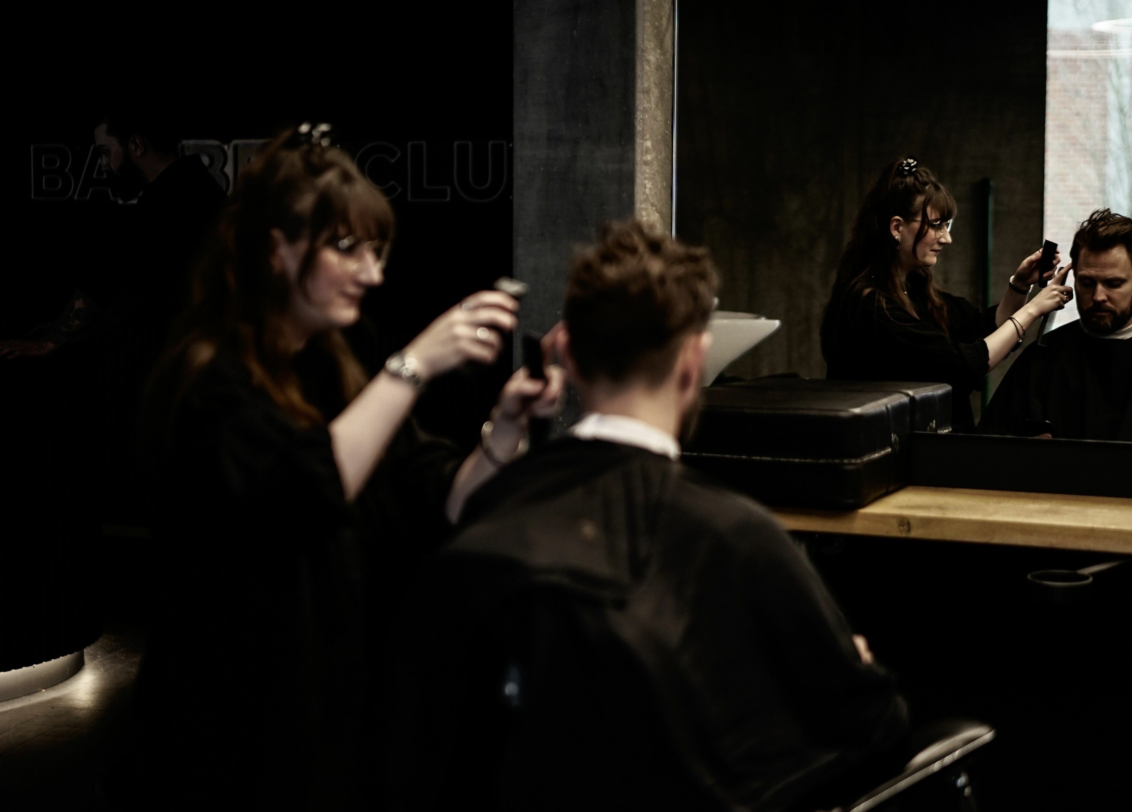 Frisør arbejder hos Barber Club i Aalborg, DK. Moderne salonstemning og professionel hårpleje.