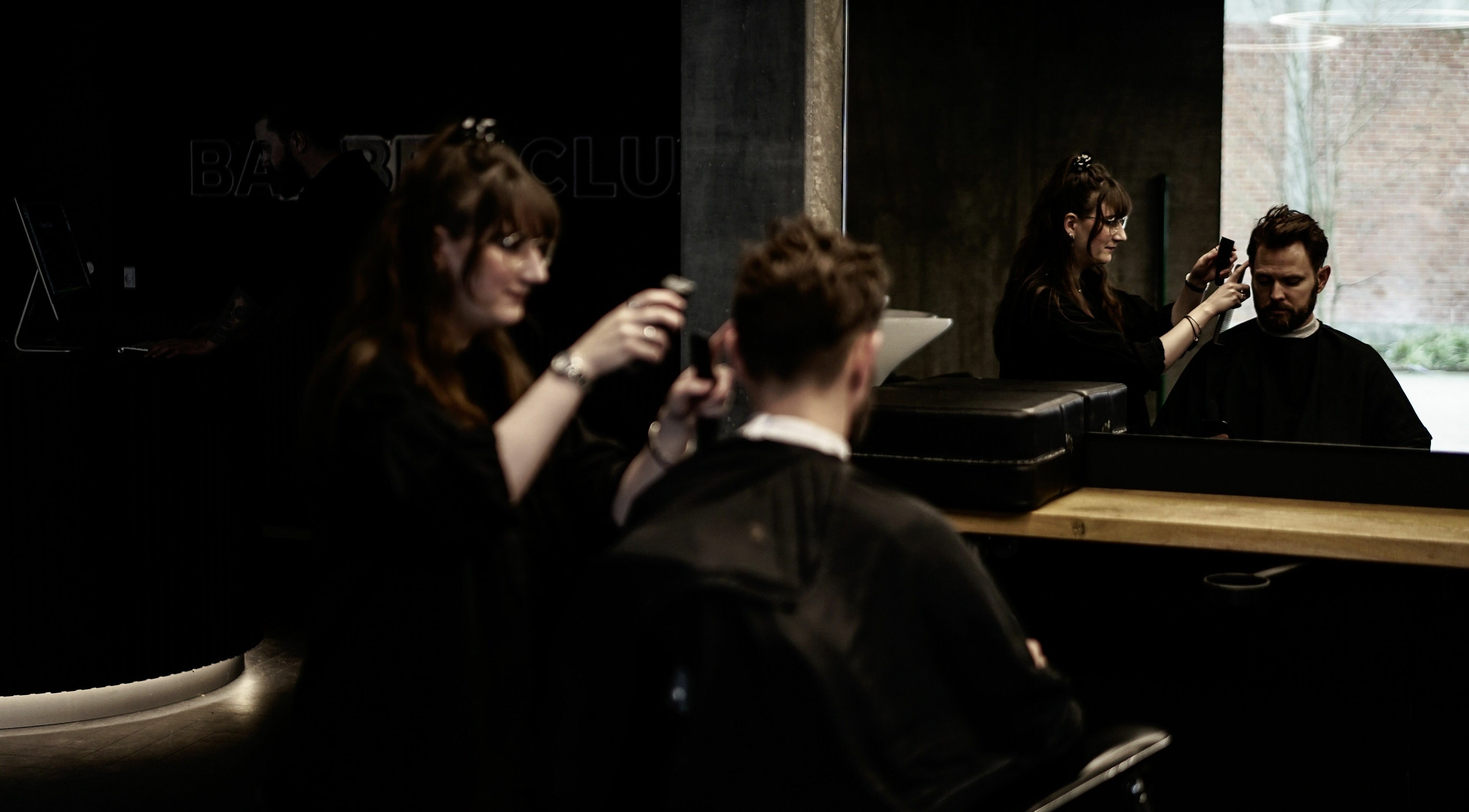 Frisør arbejder hos Barber Club i Aalborg, DK. Moderne salonstemning og professionel hårpleje.