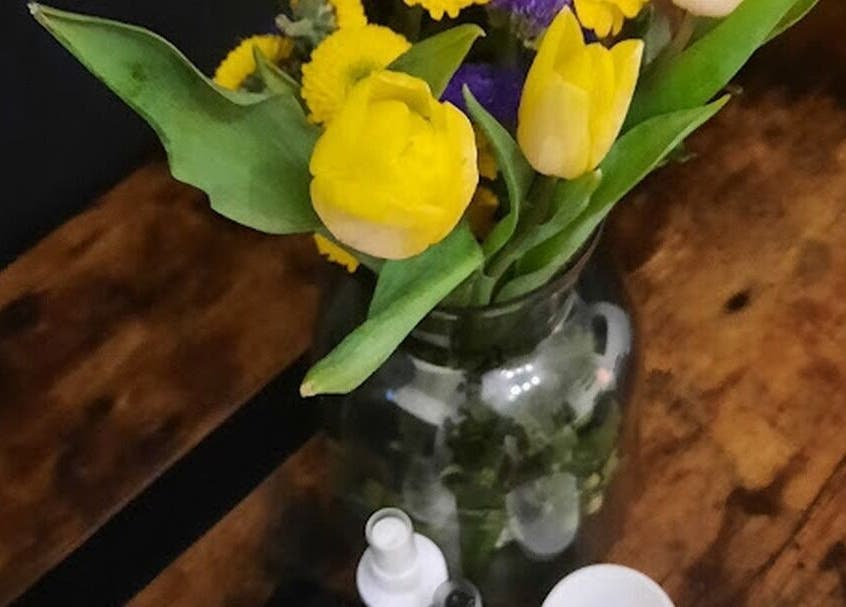 Fresh yellow tulips in a vase on a wooden table at Soul Bliss with Sayyada, Tamworth, England, GB.