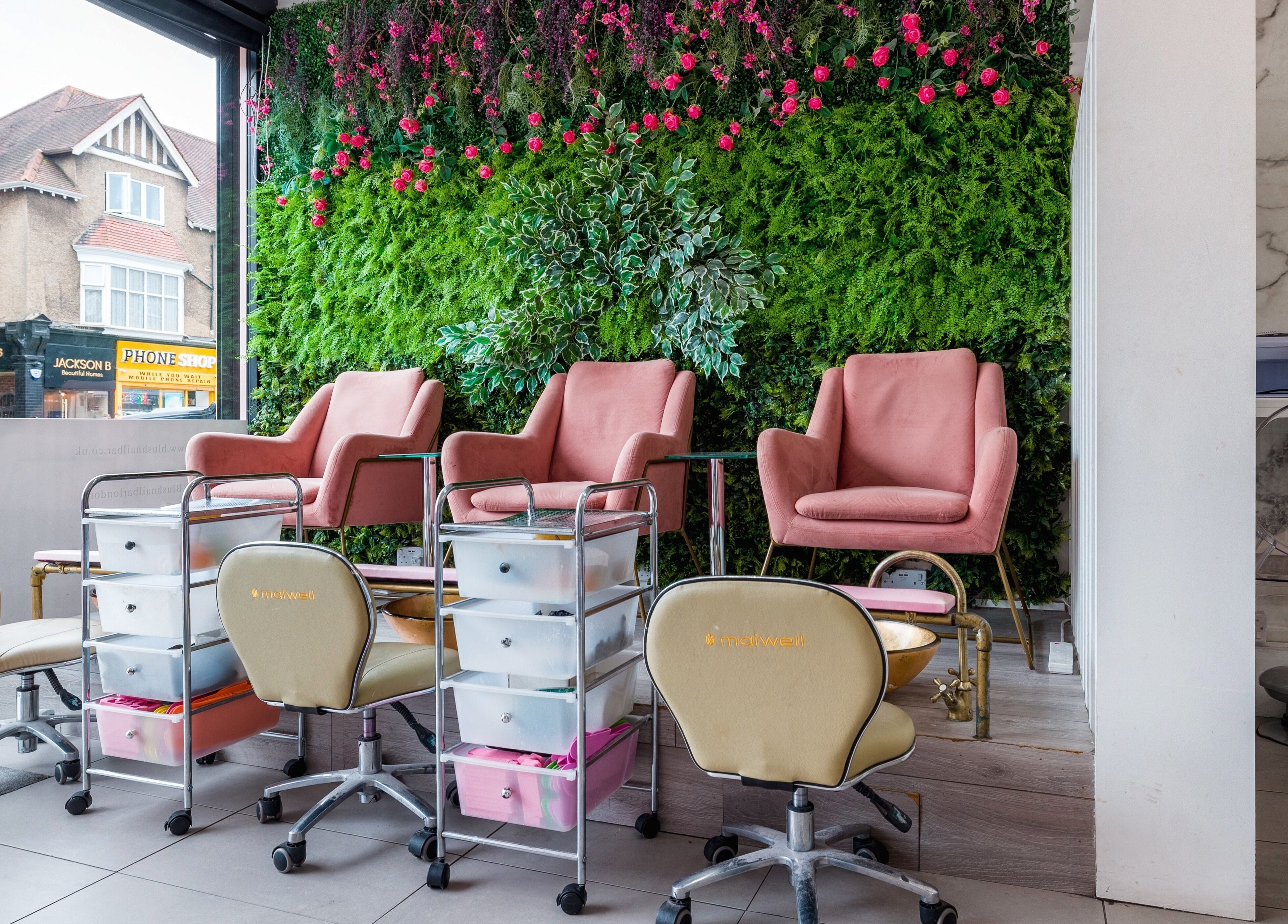 Luxurious nail spa chairs at Blush Nail Bar, London, England, GB, with a vibrant green and floral backdrop.