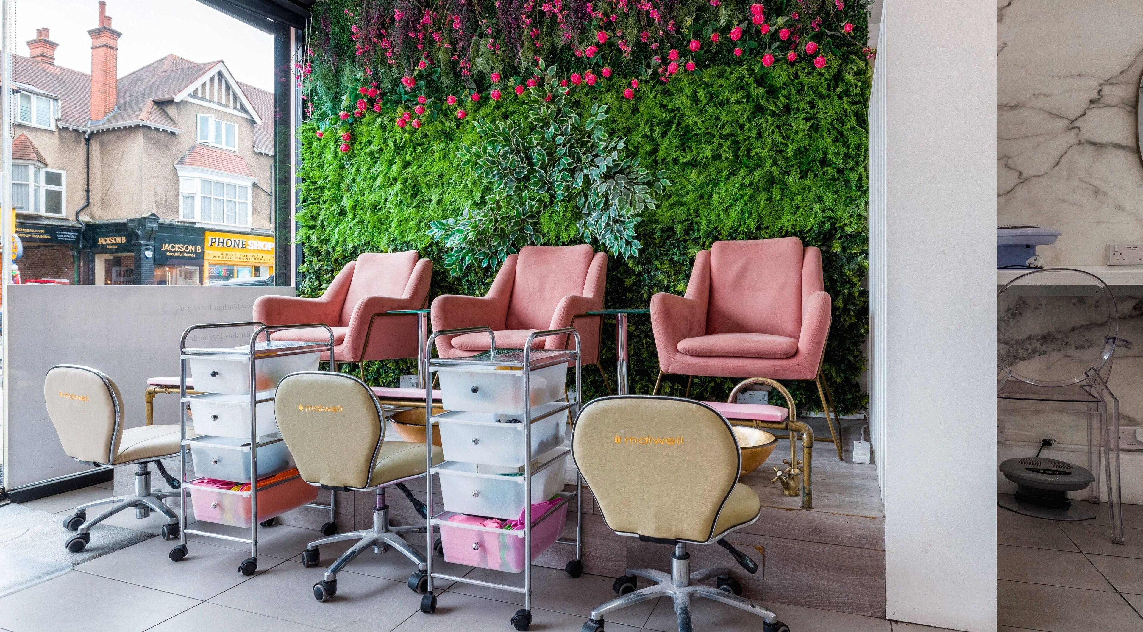 Luxurious nail spa chairs at Blush Nail Bar, London, England, GB, with a vibrant green and floral backdrop.