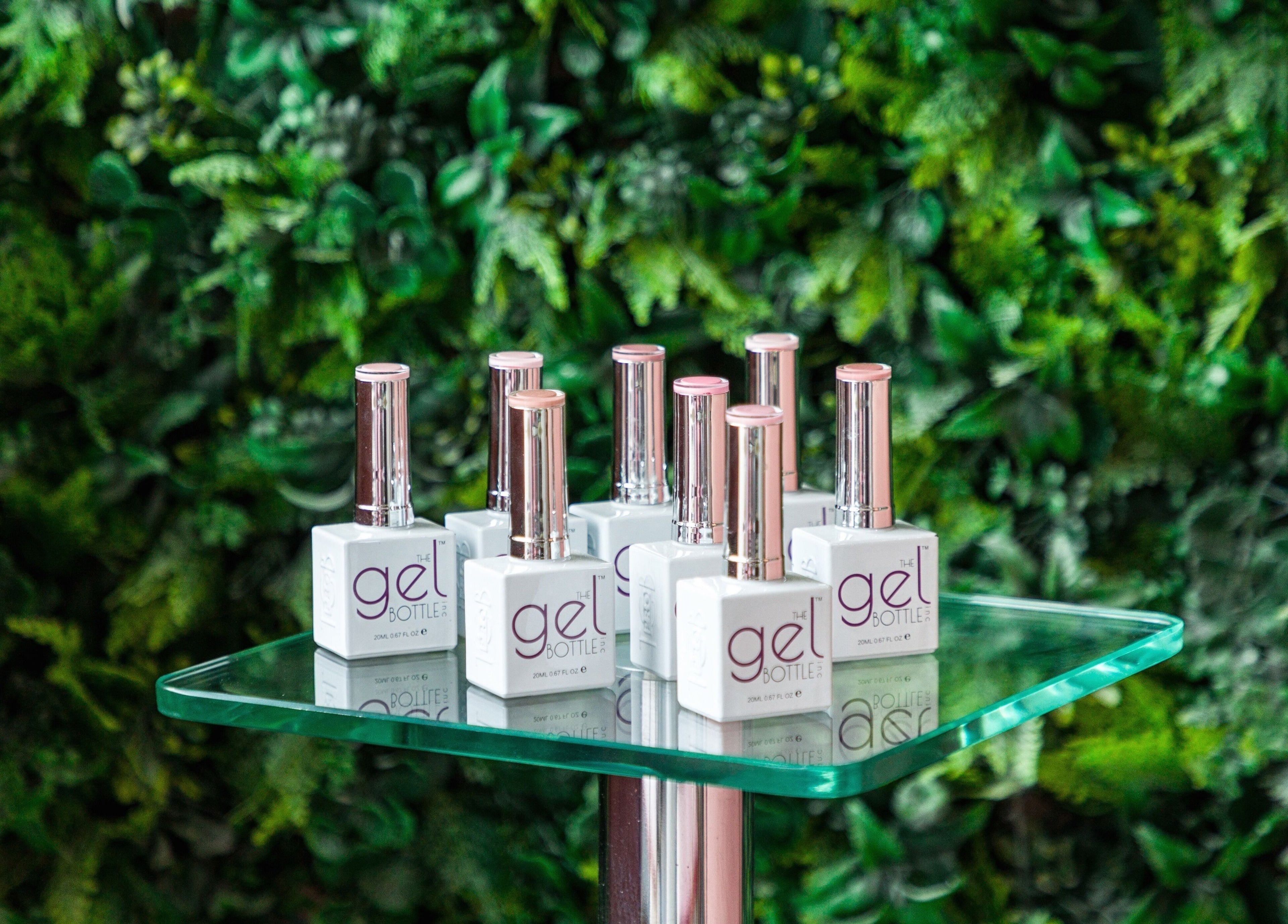 Gel nail polish on glass stand at Blush Nail Bar, London, England, GB with lush green backdrop.