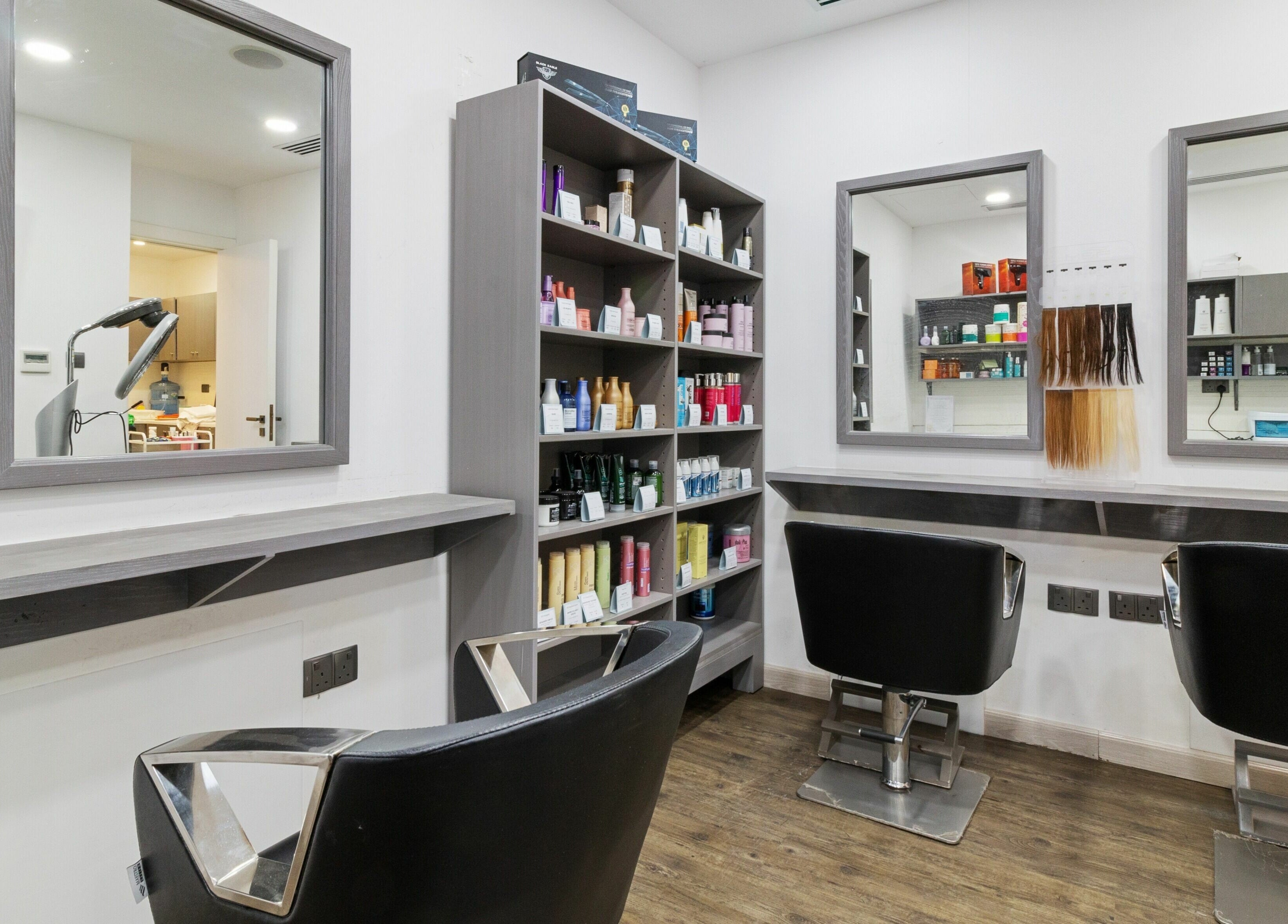 Modern salon interior at Inspire Spa in Abu Dhabi, showcasing sleek mirrors and styling chairs.