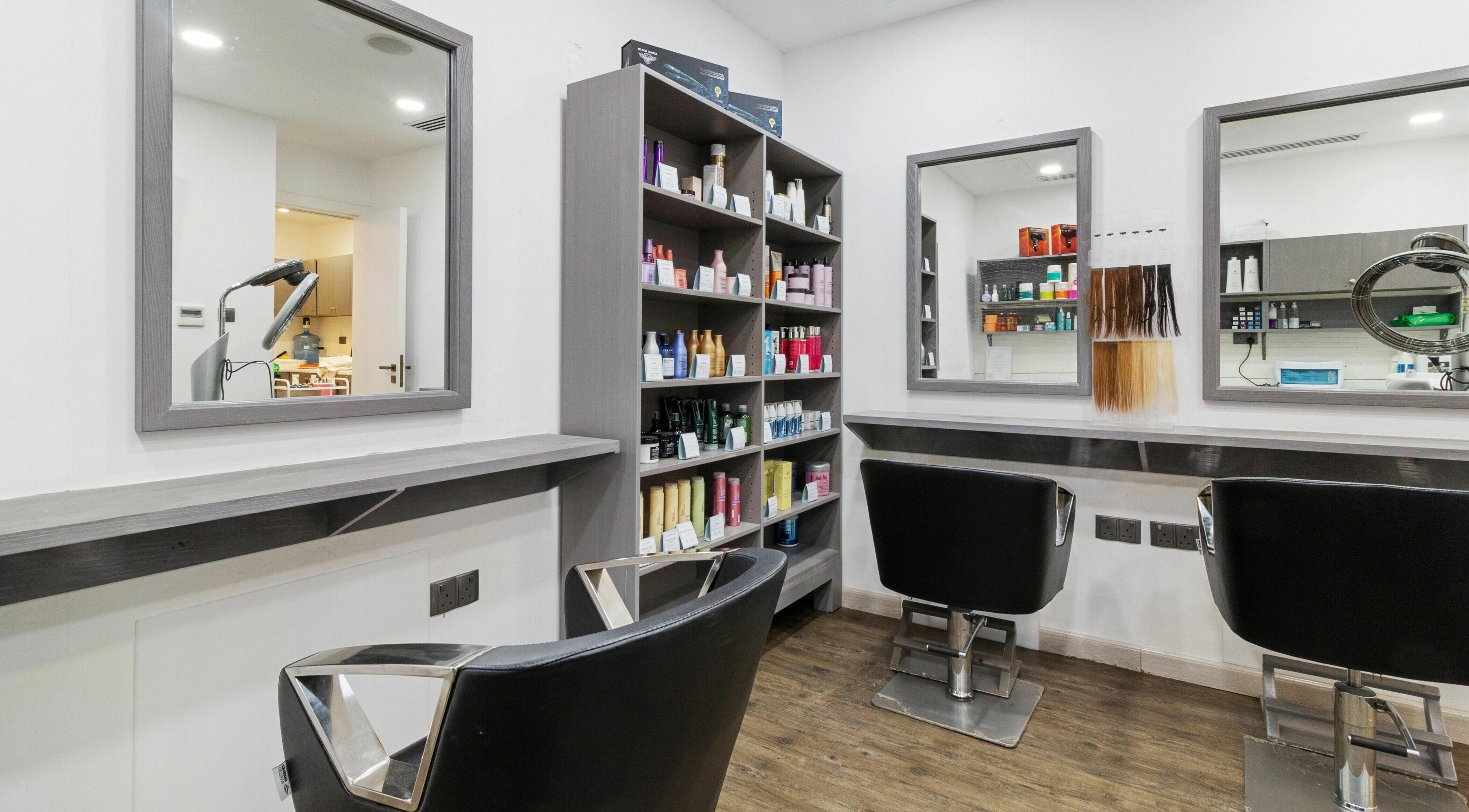 Modern salon interior at Inspire Spa in Abu Dhabi, showcasing sleek mirrors and styling chairs.