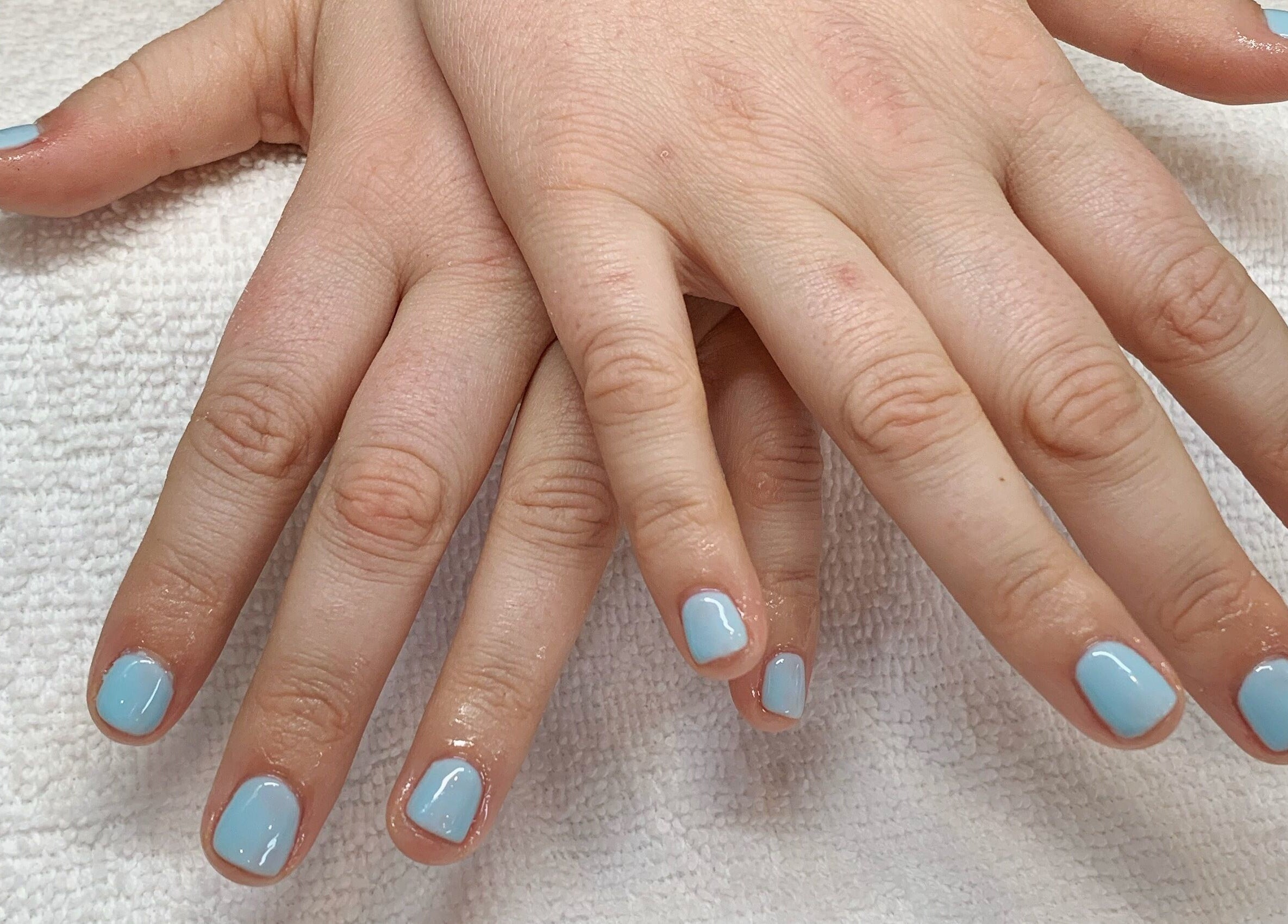Fresh blue manicure at Sidney Aesthetics, Owen Sound, Ontario, CA showcasing soft, glossy nails.