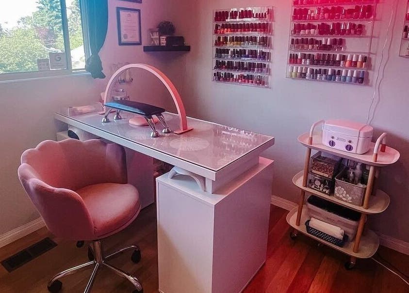 Chic nail salon setup at Esthetics by Lyss, Nanaimo, BC, CA; featuring elegant pink chair and polish display.