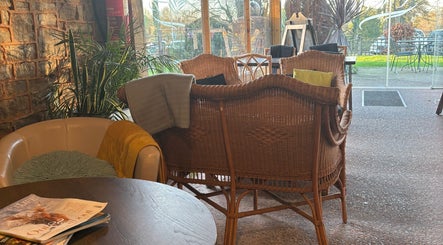 Relaxing lounge area at CJ Soft Tissue & Massage Therapy in Wellington, England, GB with wicker chairs and greenery.