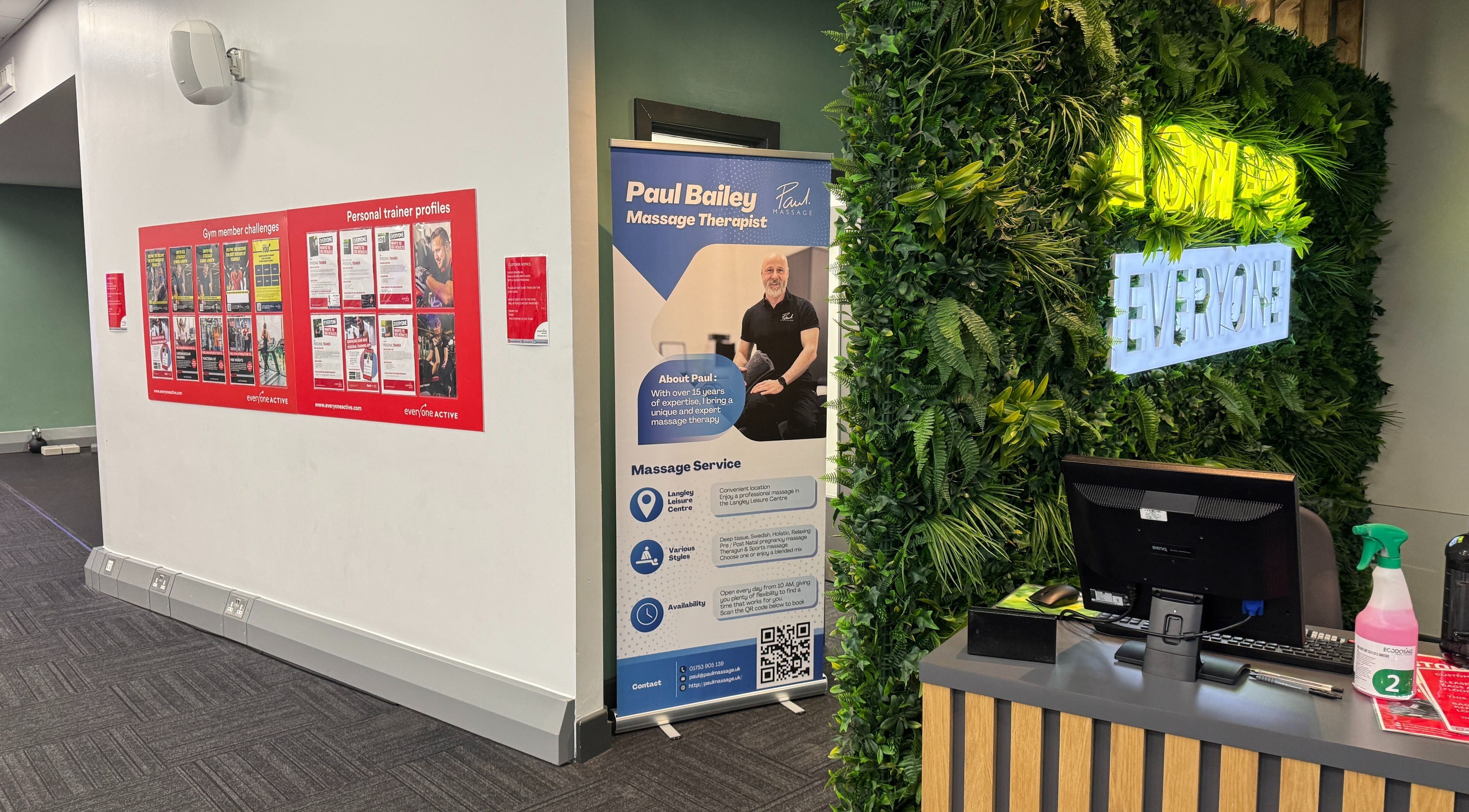 Reception at Paul Massage in Langley Leisure Centre, Slough, England, featuring lush green décor and promotional display.