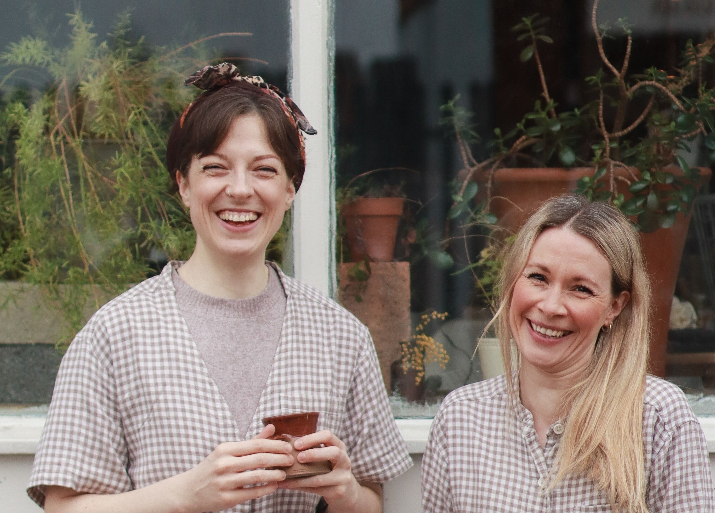 Team members at Harvest Skincare, Birmingham, England, GB, smiling by a window with plants.