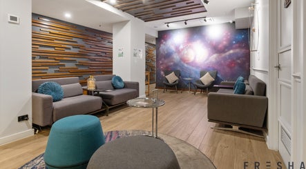 The Savoy Hotel - V Hotel Spa lounge in Melbourne, VIC, AU features modern seating and a cosmic wall mural.