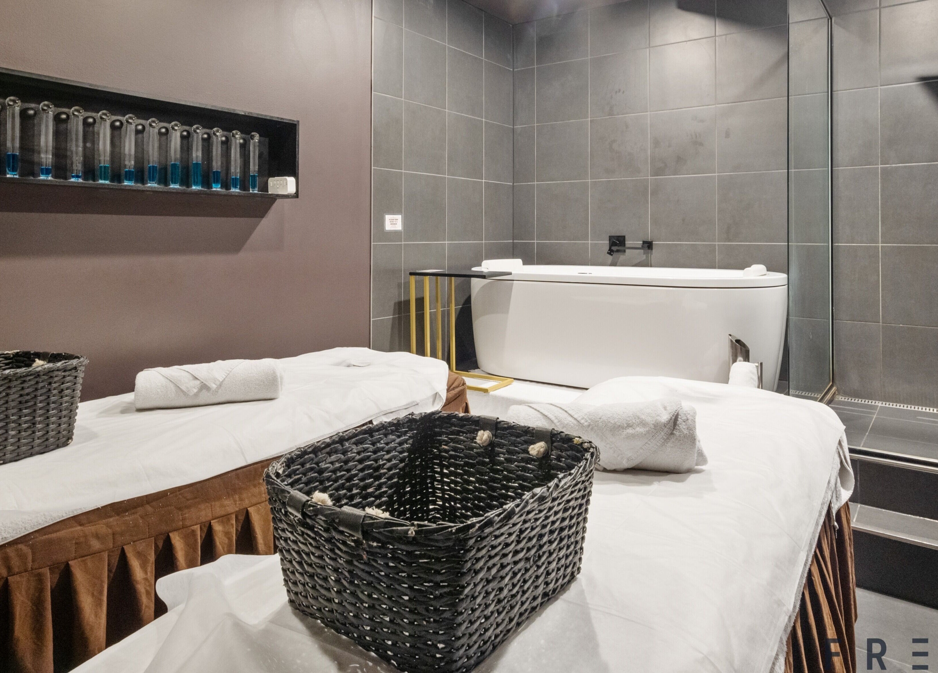 Luxurious spa room at The Savoy Hotel - V Hotel Spa, Melbourne, VIC, AU featuring a modern bathtub and massage tables.