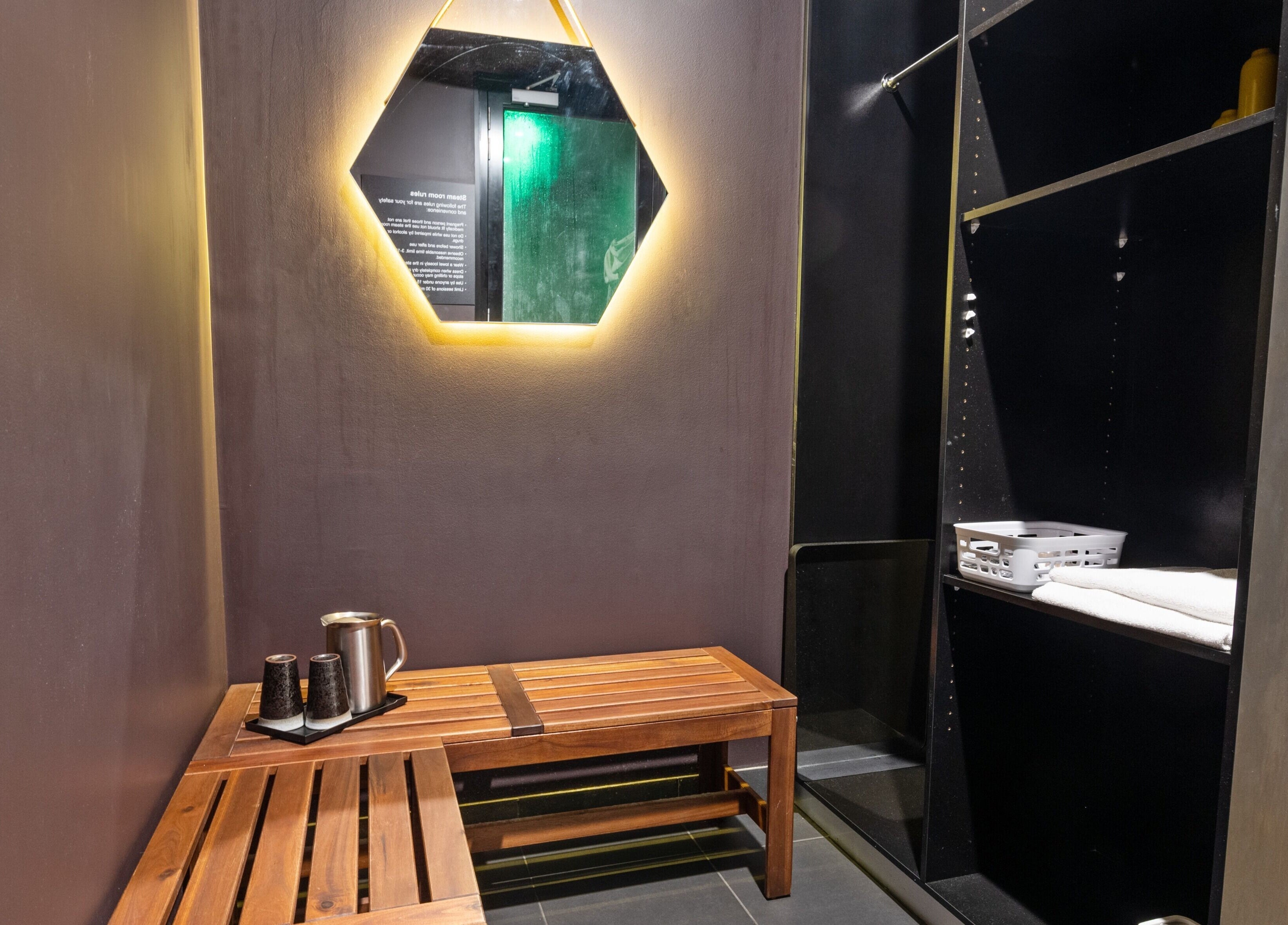 Relaxing seating area at The Savoy Hotel - V Hotel Spa, Melbourne, VIC, AU with mirror and wooden bench.