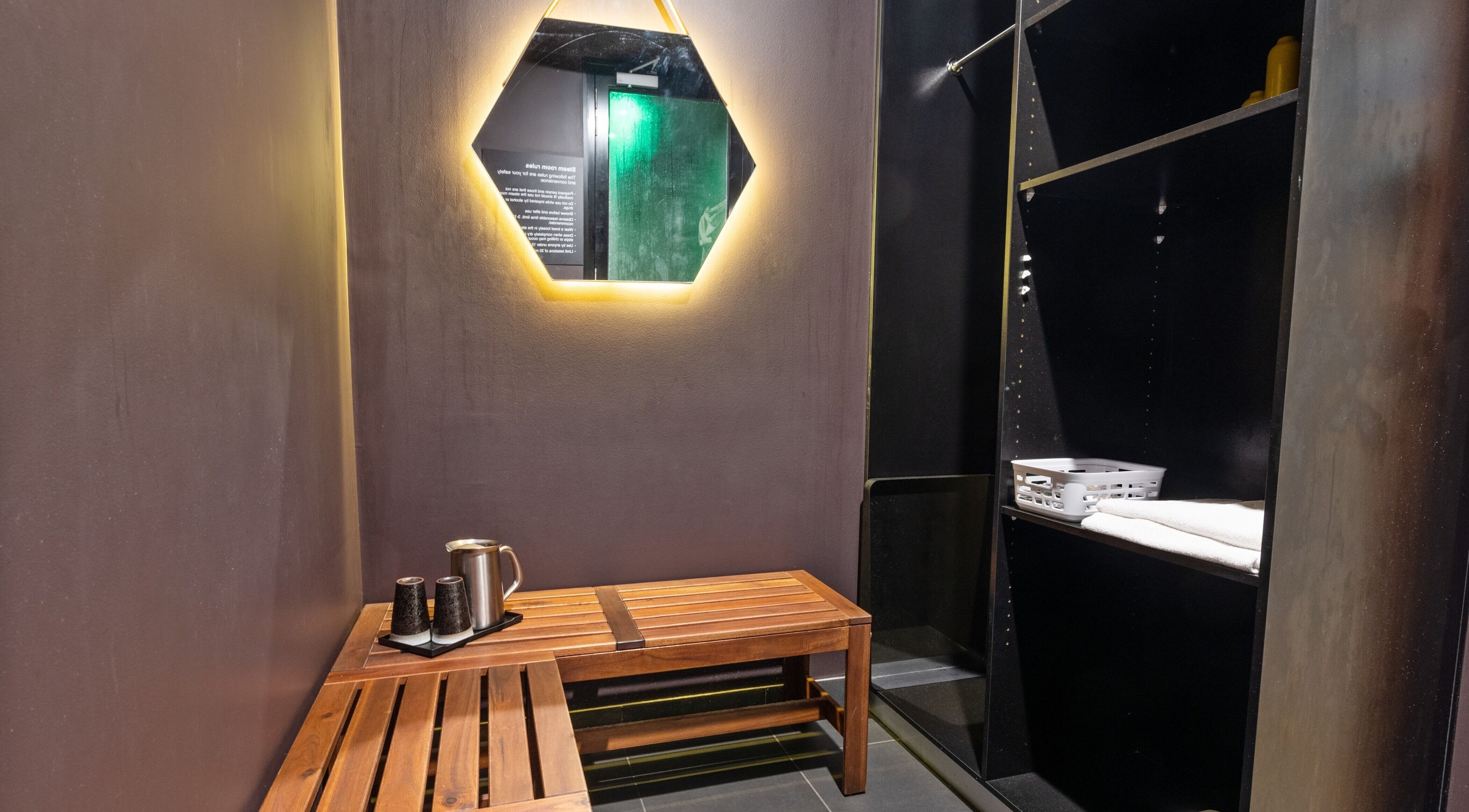 Relaxing seating area at The Savoy Hotel - V Hotel Spa, Melbourne, VIC, AU with mirror and wooden bench.