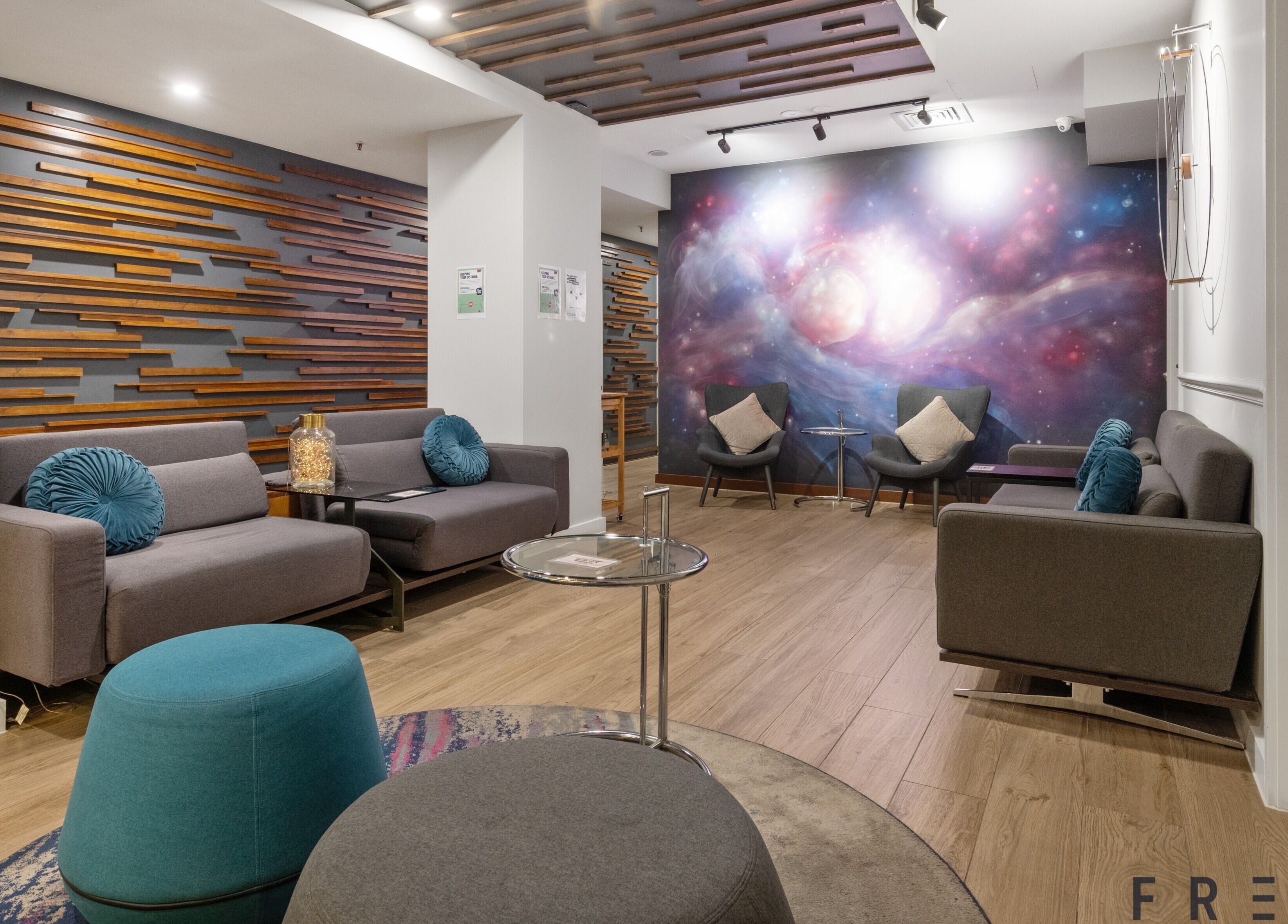 Relaxing lounge at The Savoy Hotel - V Hotel Spa, Melbourne, VIC, AU with cosmic wall art and modern decor.