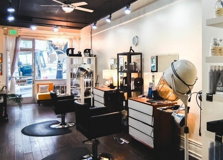 Interior of Dolled and Dapper Salon in San Francisco, California, US, showcasing stylish chairs and beauty products.