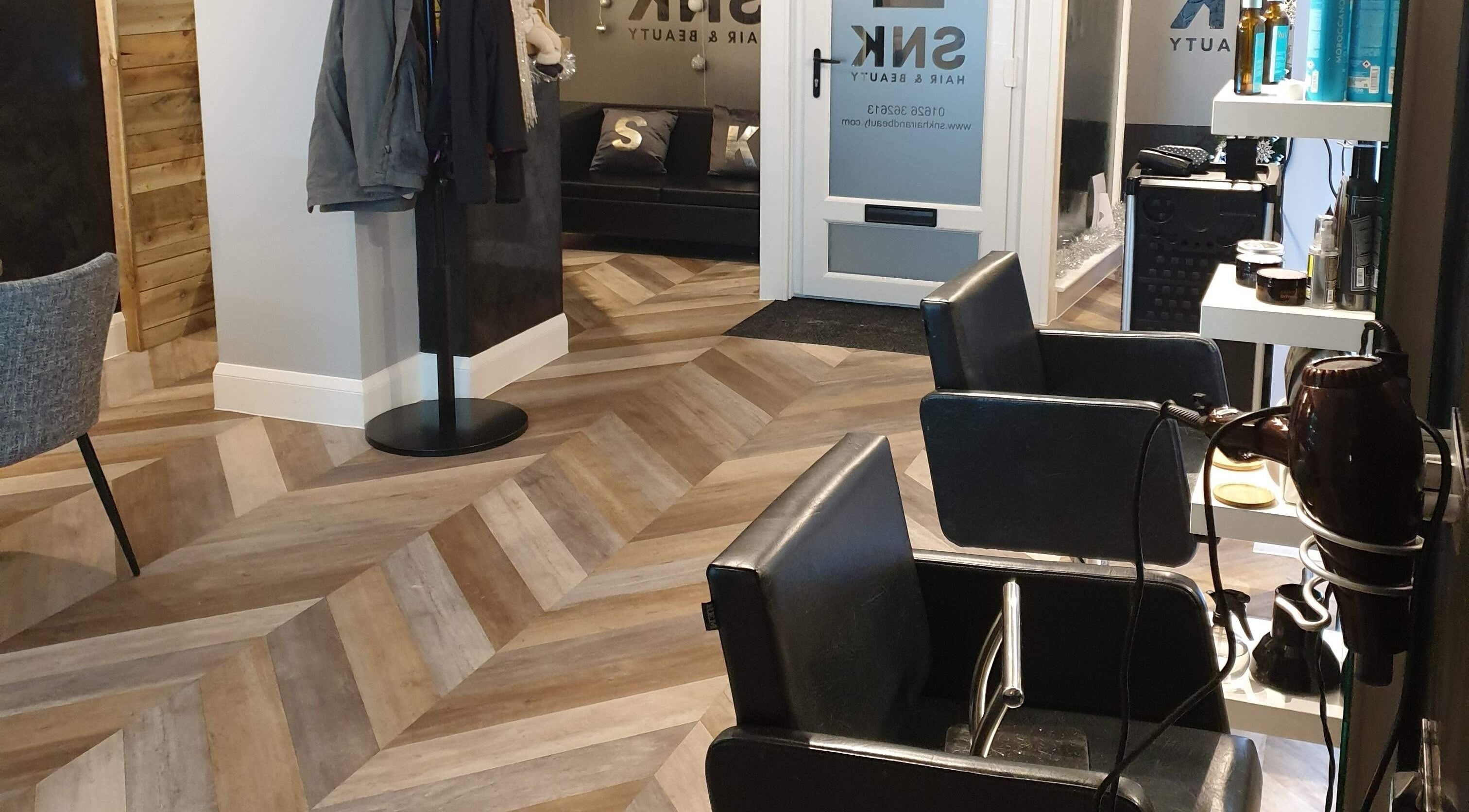 Modern interior of Snk Hair & Beauty, Newton Abbot, England, GB featuring sleek styling chairs and wooden flooring.