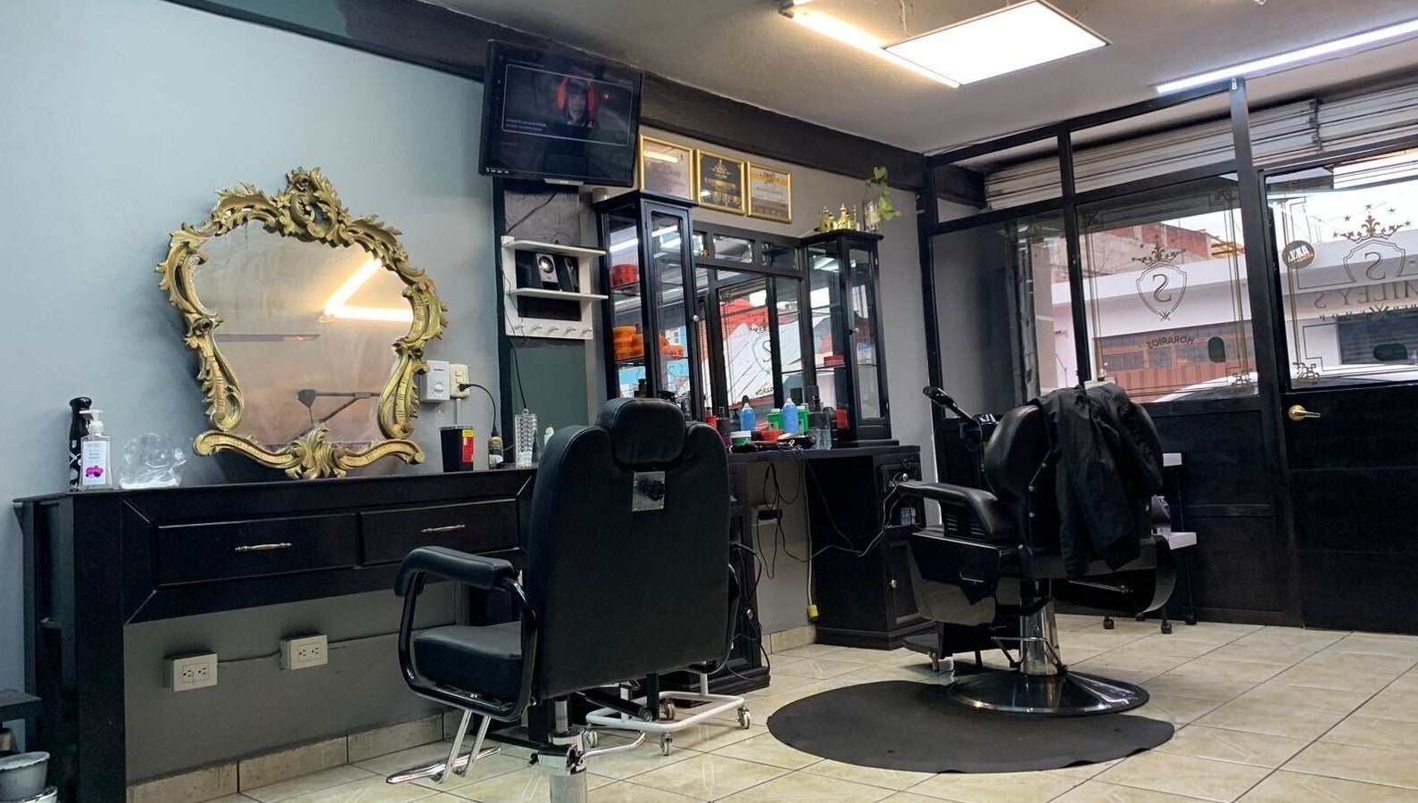 Interior de Smiley Barber Studio en Uruapan, Michoacán, MX, mostrando sillas de barbero y espejo dorado elegante.