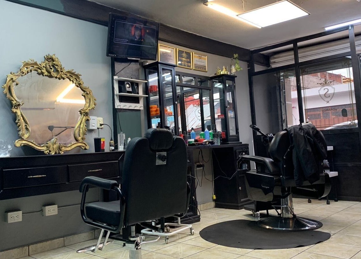 Interior de Smiley Barber Studio en Uruapan, Michoacán, MX, mostrando sillas de barbero y espejo dorado elegante.
