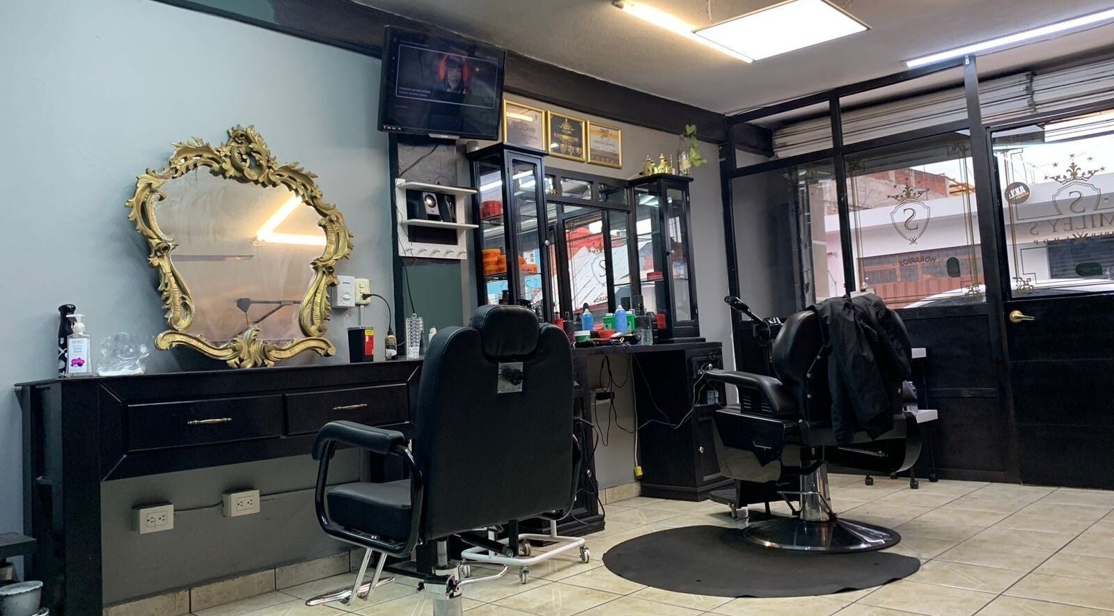 Interior de Smiley Barber Studio en Uruapan, Michoacán, MX, mostrando sillas de barbero y espejo dorado elegante.