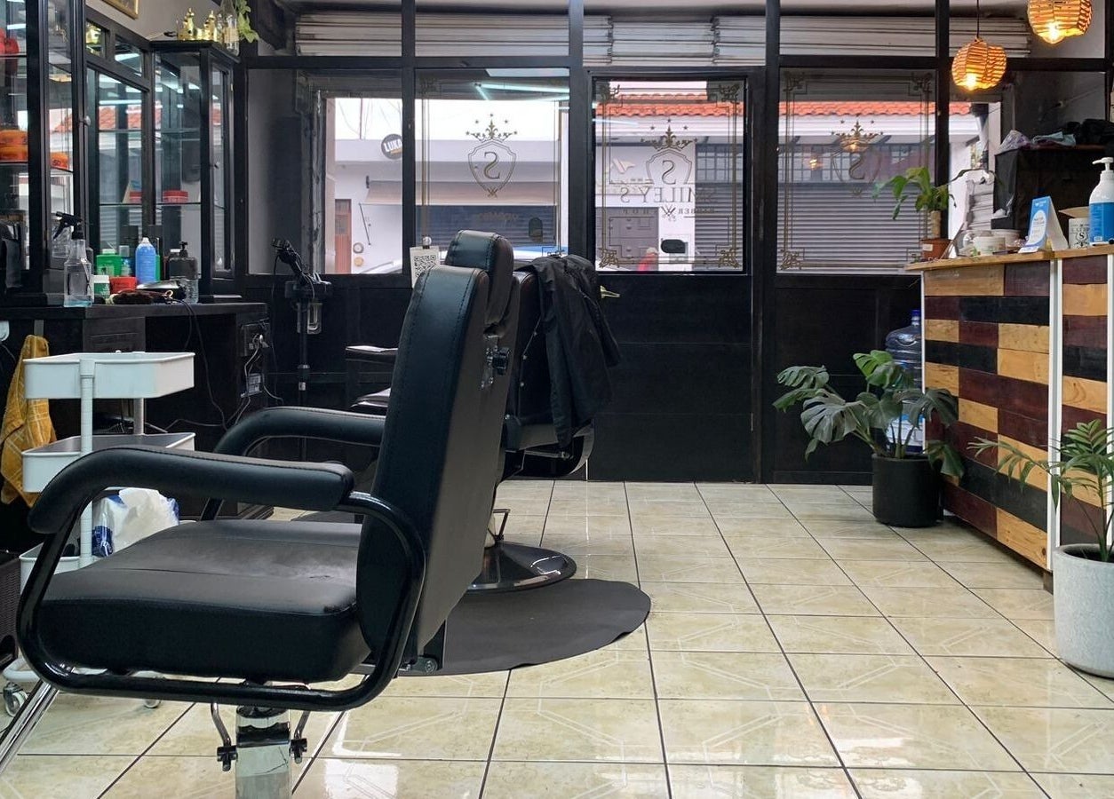 Interior de Smiley Barber Studio en Uruapan, Michoacán, MX, con asientos de barbería modernos y elegante decoración.
