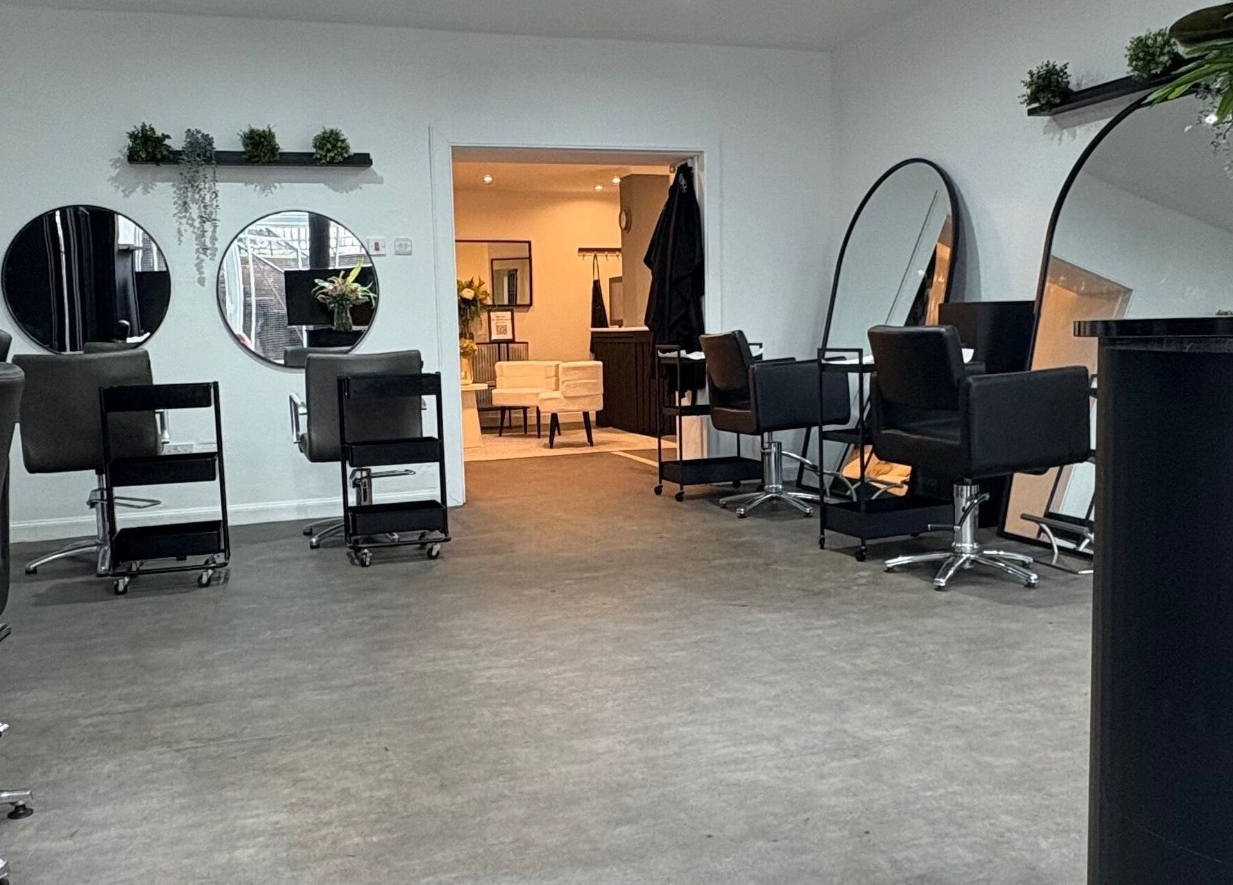 Modern interior of The Collective Hair Co salon in Glasgow, Scotland with stylish black chairs and mirrors.