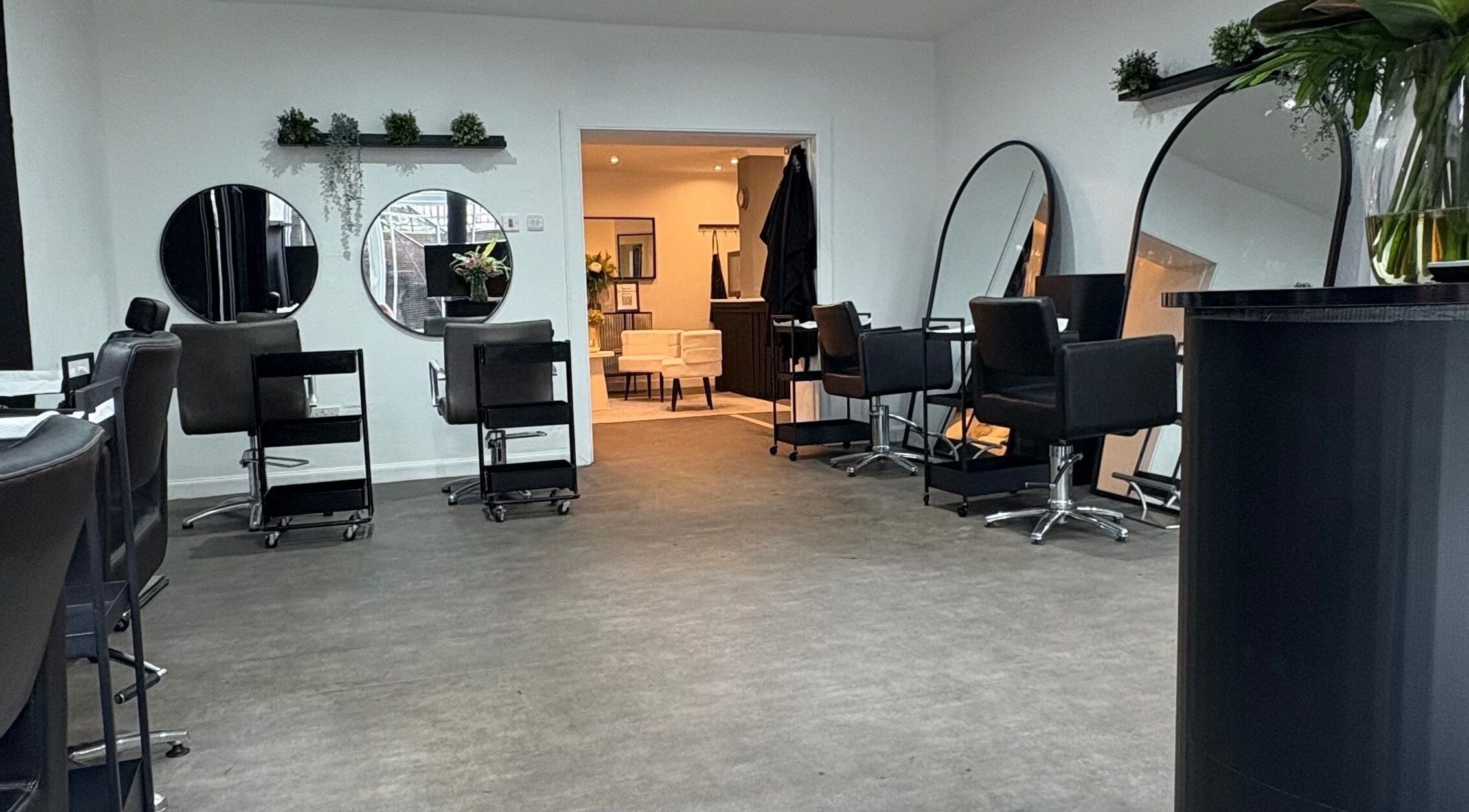 Modern interior of The Collective Hair Co salon in Glasgow, Scotland with stylish black chairs and mirrors.