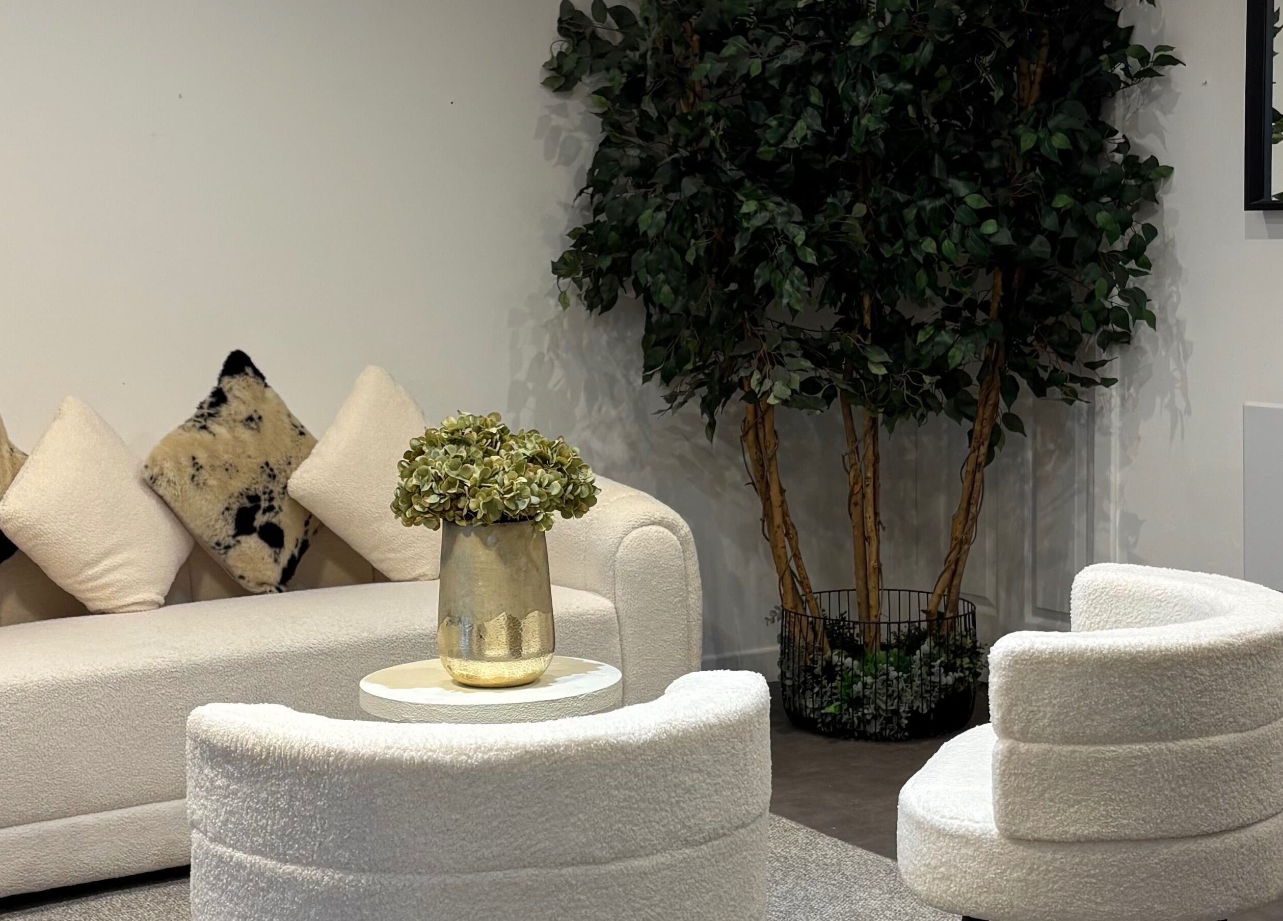 Elegant lounge area at The Collective Hair Co, Glasgow, Scotland, GB, featuring plush seating and lush greenery.