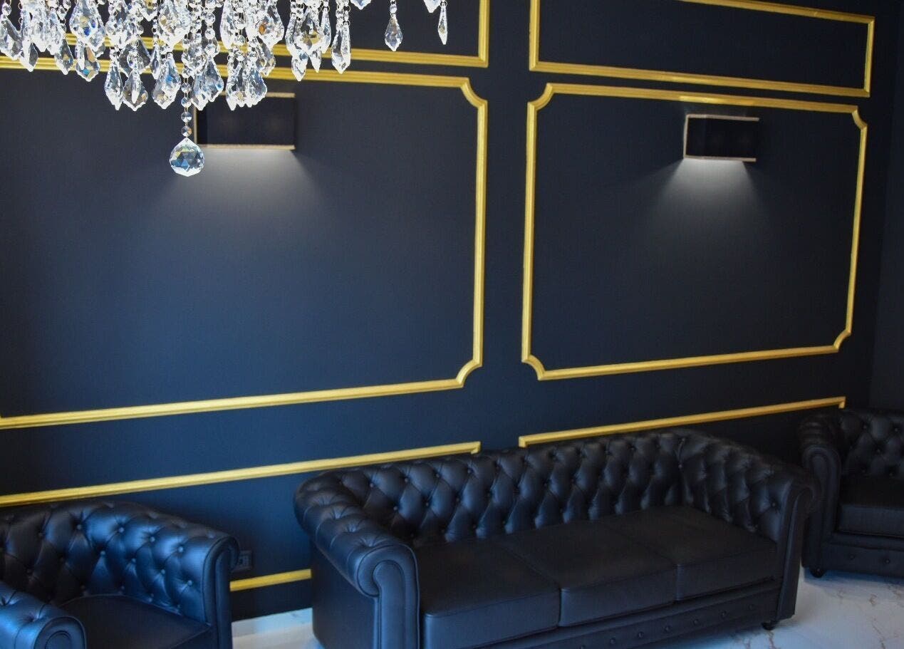 Salotto elegante al Blackout Concept di Terracina, Lazio, con divani in pelle nera e dettagli dorati.
